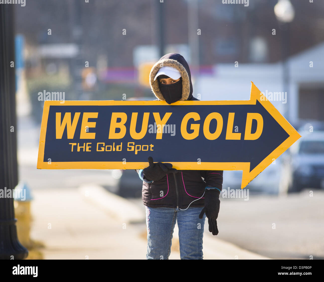 ARLINGTON, VIRGINIA, USA - Woman holds We Buy Gold sign on sidewalk to attract customers. Stock Photo