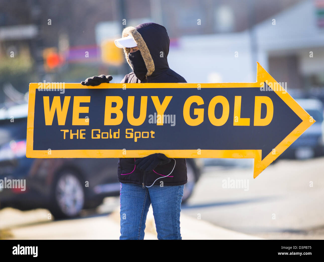 ARLINGTON, VIRGINIA, USA - Woman holds We Buy Gold sign on sidewalk to
