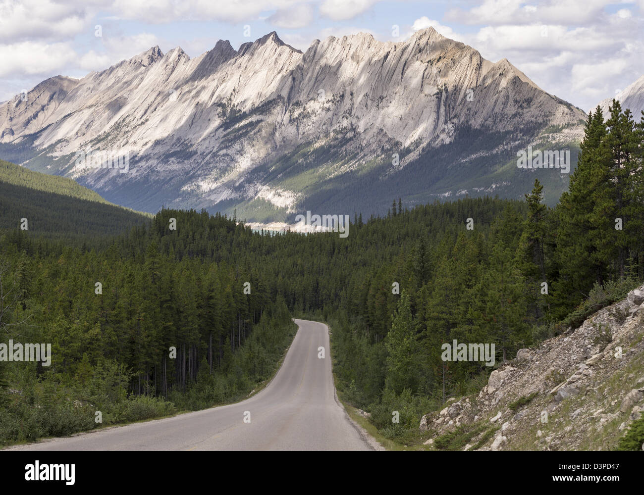 Majestic Mountains rise high above Medicine lake. The Road from Maligne Lake curves toward Medicine Lake. Stock Photo