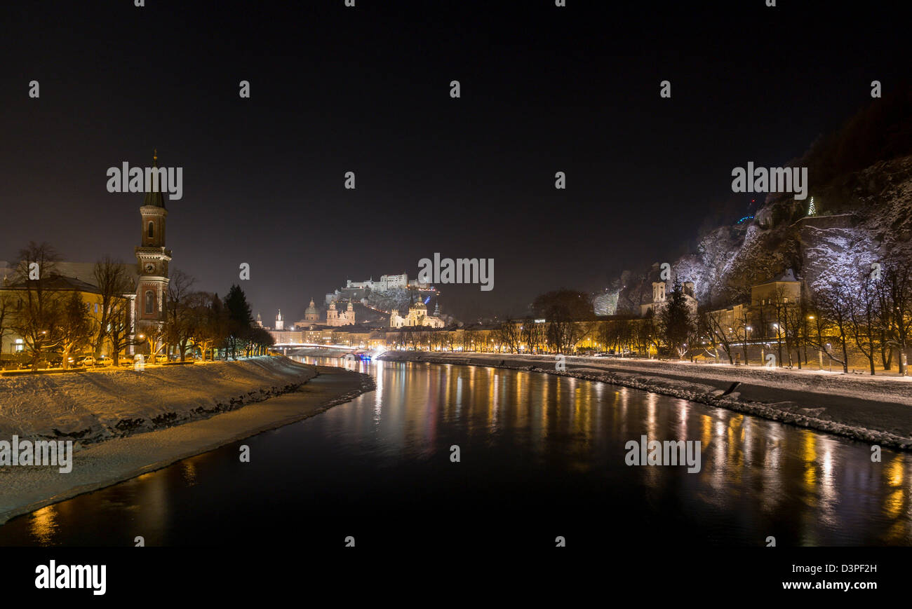Evening Winter view of the old centre of Salzburg. The Salzach River reflects the lights of the city and the castle. Stock Photo