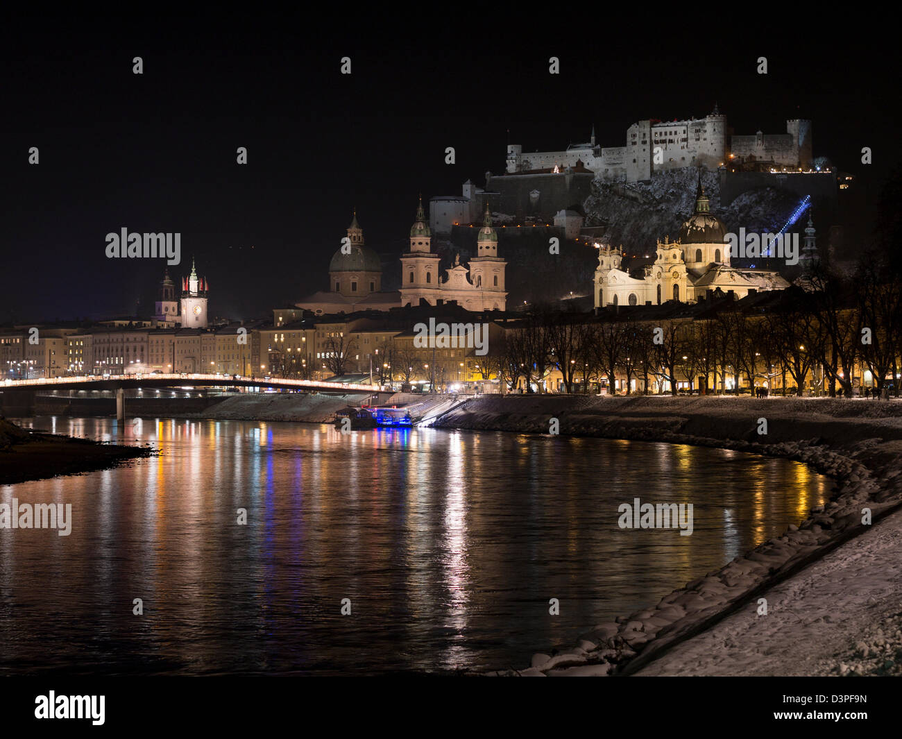 Evening Winter view of the old centre of Salzburg. The Salzach River reflects the lights of the city and the fortress above Stock Photo