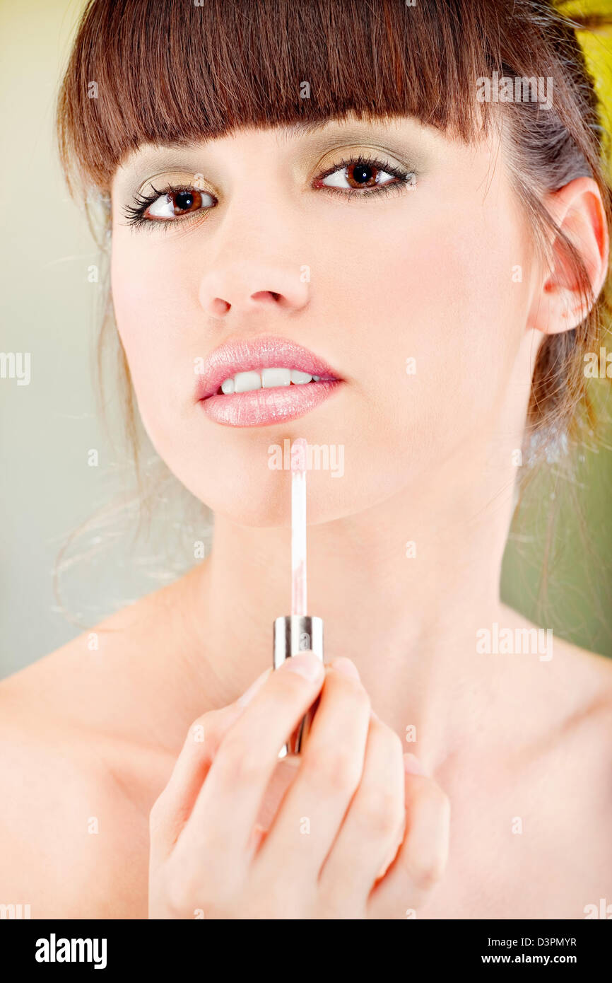 Pretty woman putting lipstick on her lips Stock Photo