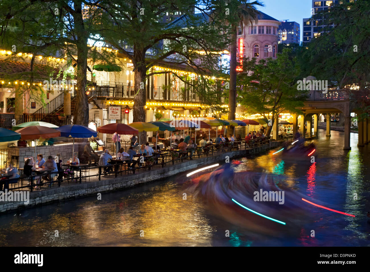 Colorful umbrellas, boat light streaks on San Antonio River and Riverwalk, San Antonio, Texas USA Stock Photo