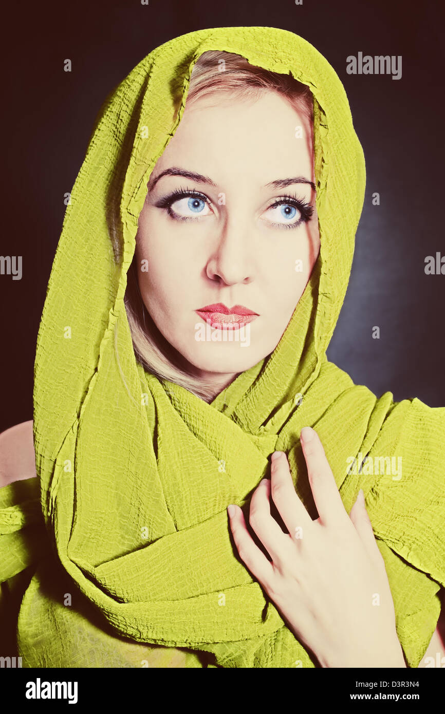 Portrait of beautiful young woman in bright, green head scarf on black