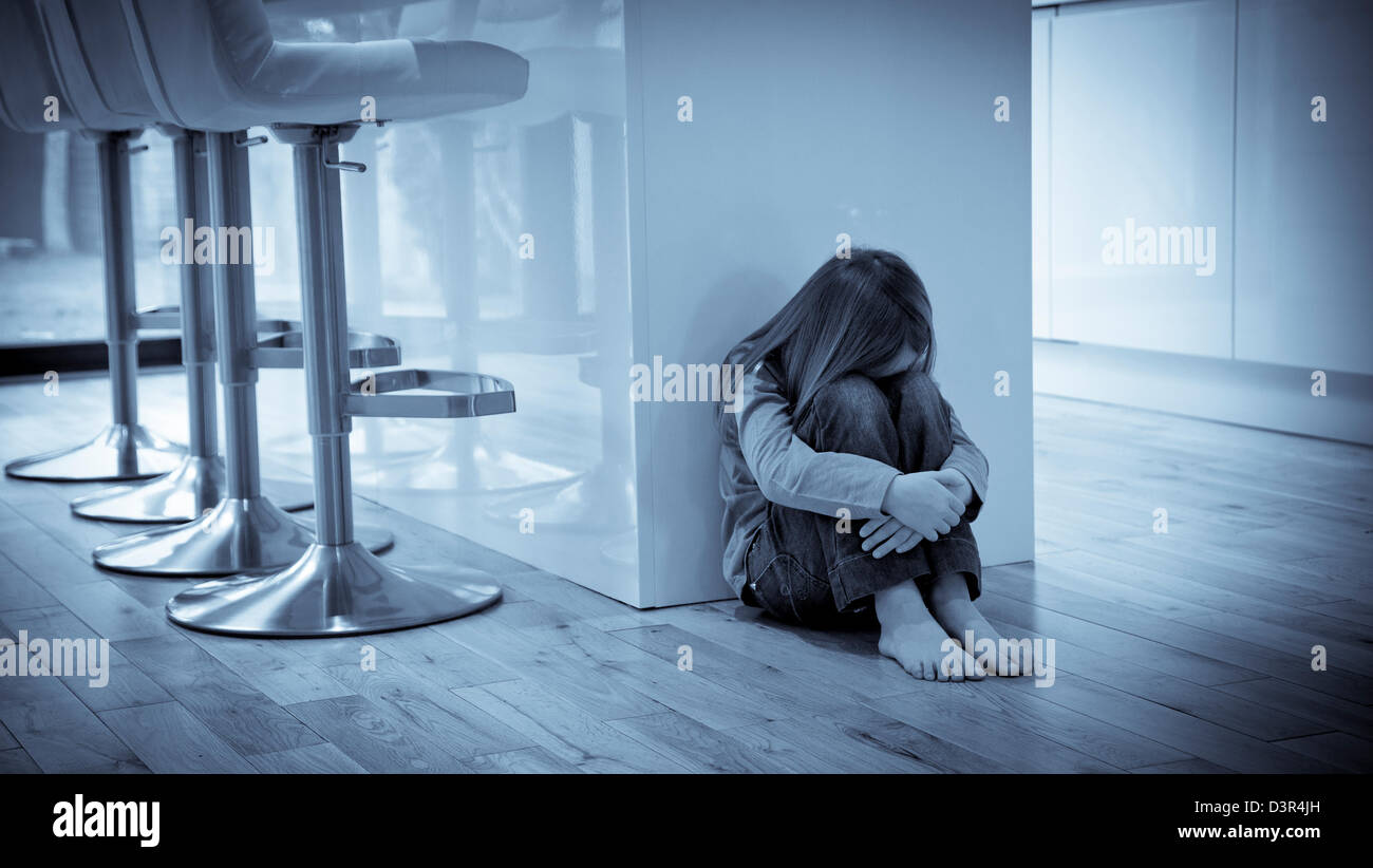 Young girl sat unhappy on the floor Stock Photo