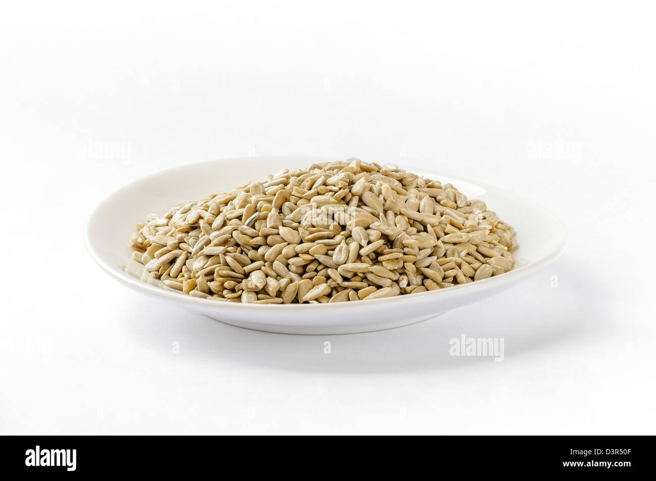Sunflower seeds in a white plate, on white background Stock Photo