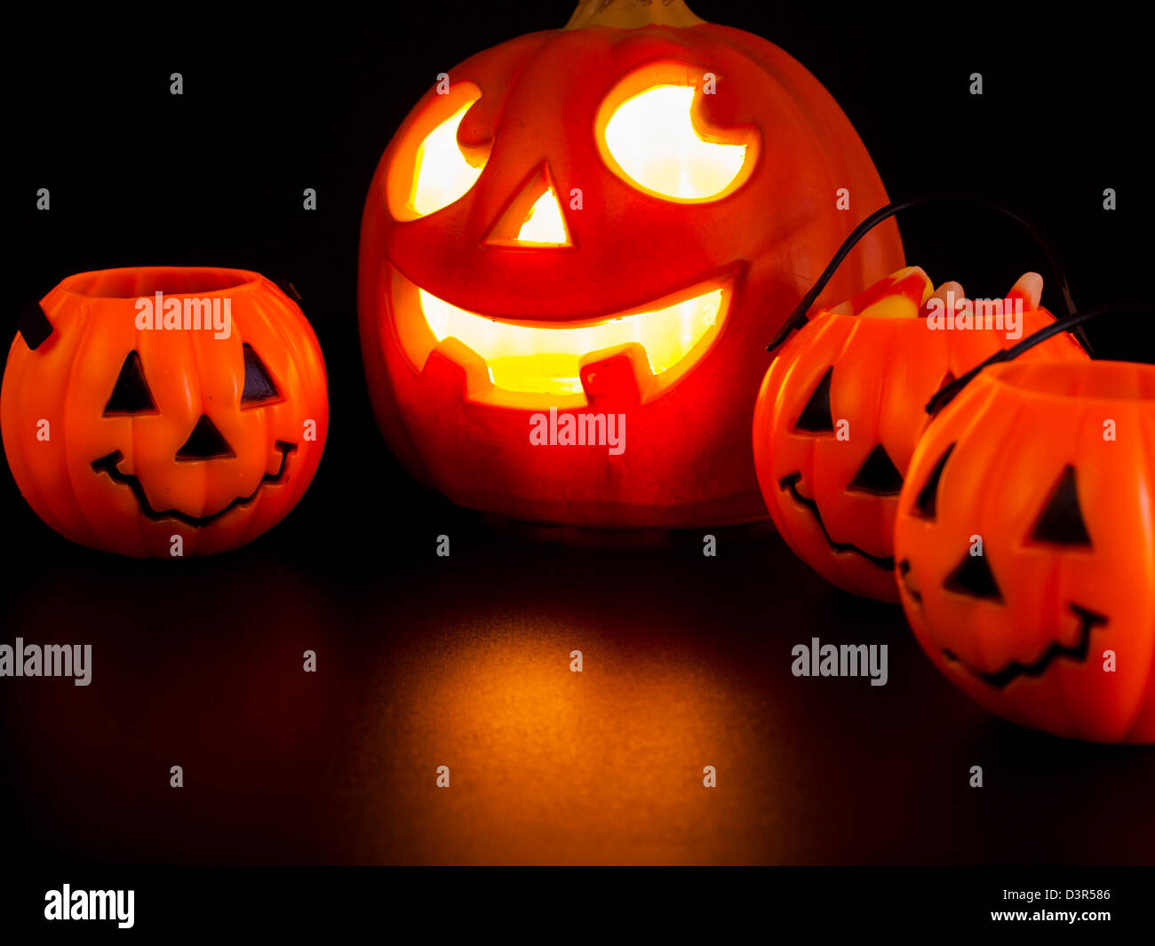 Lit jack-o'-lantern with Halloween pumpkin bags on black background ...