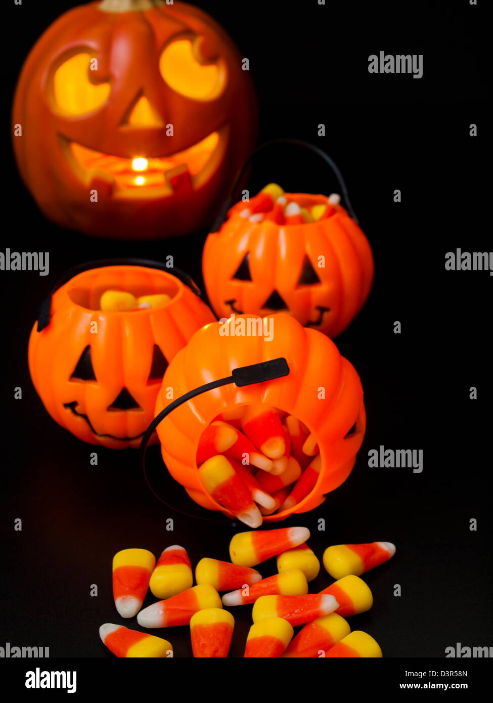 Lit jack-o'-lantern with Halloween pumpkin bags on black background ...