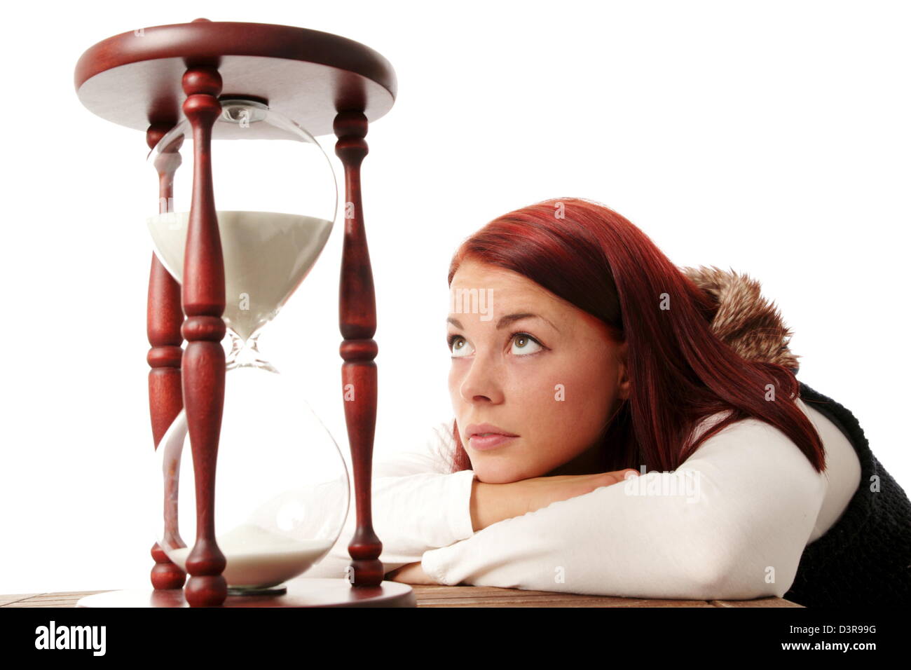 Young woman looking up to a big hourglass Stock Photo