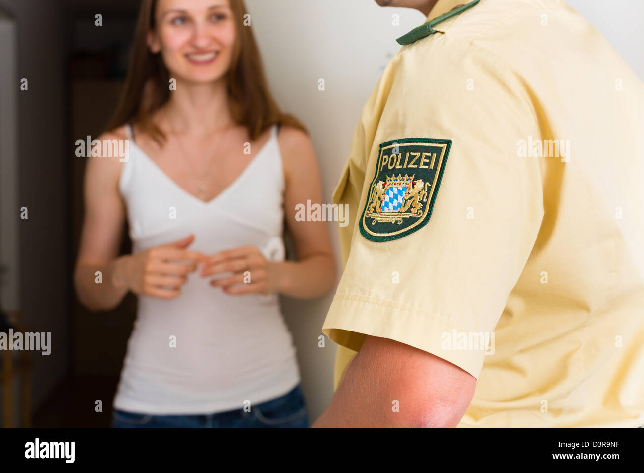 Police officer at front door of home interrogating a woman or witness regarding a police investigation Stock Photo
