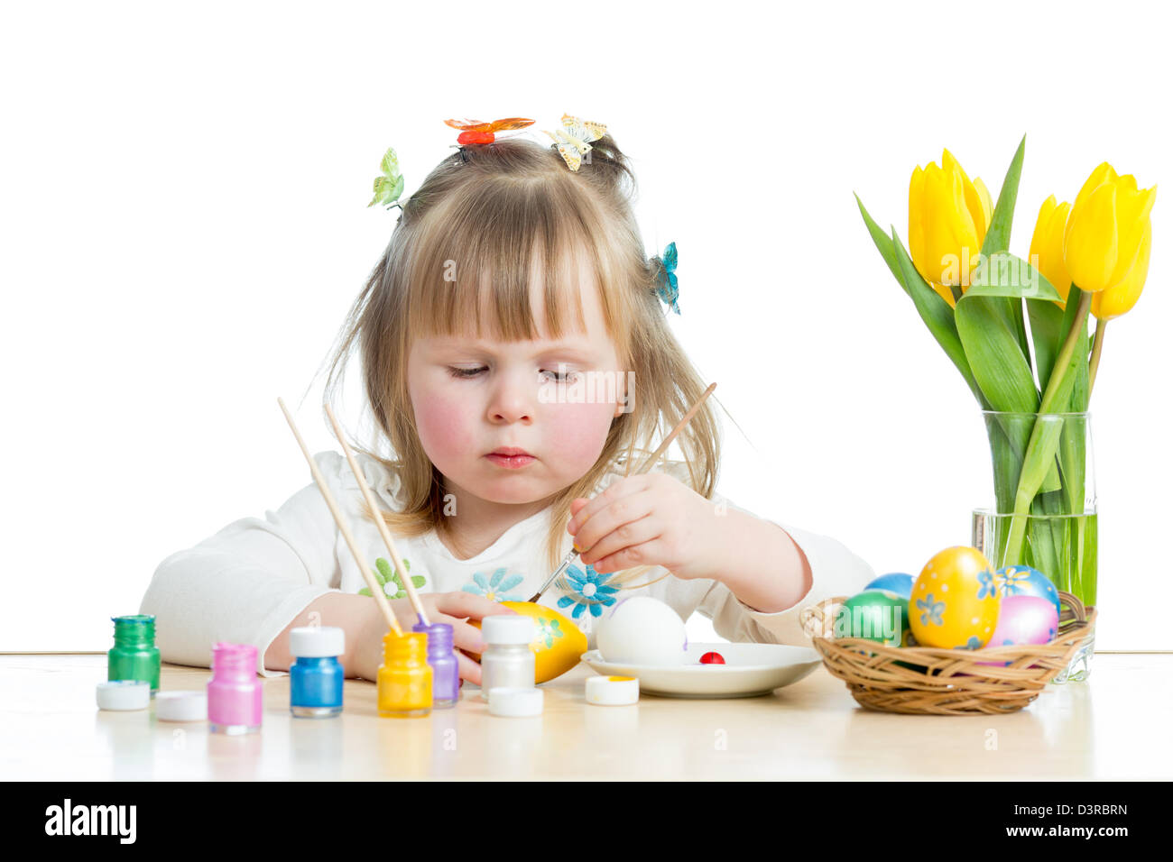 baby girl painting Easter eggs isolated on white background Stock Photo