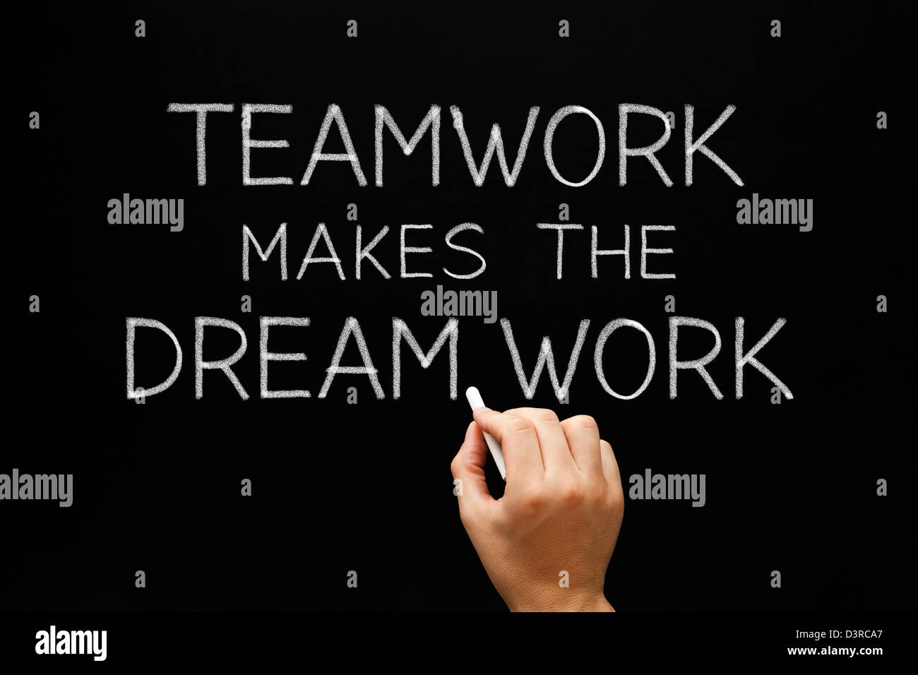 Hand writing Teamwork Makes The Dream Work with white chalk on a blackboard. Stock Photo