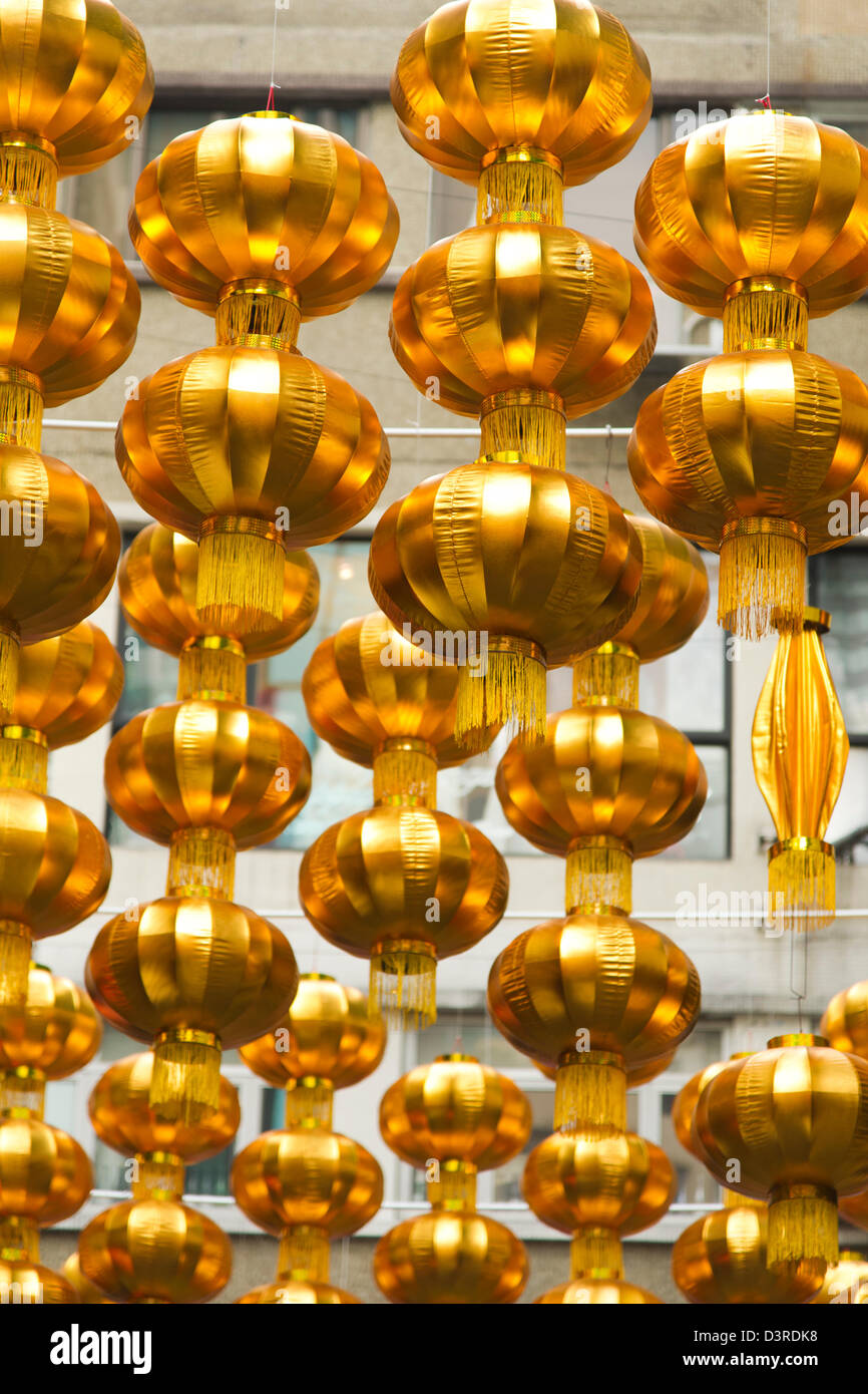 Gold Chinese New Year ornaments hang above a street in Hong Kong Stock Photo