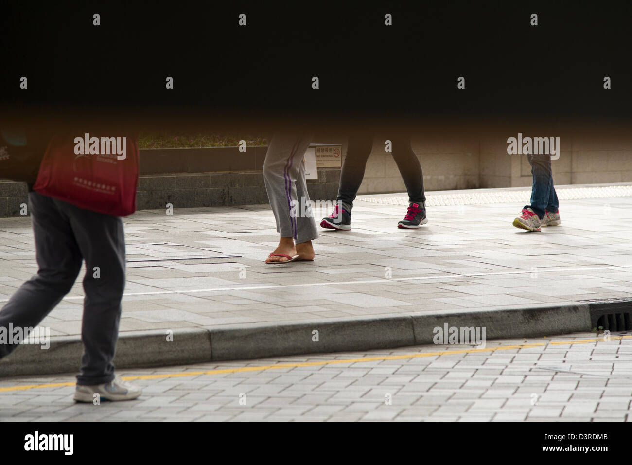 The legs and feet of passersby are visible below a barricade blocking the full view of Stanley promenade in Hong Kong Stock Photo