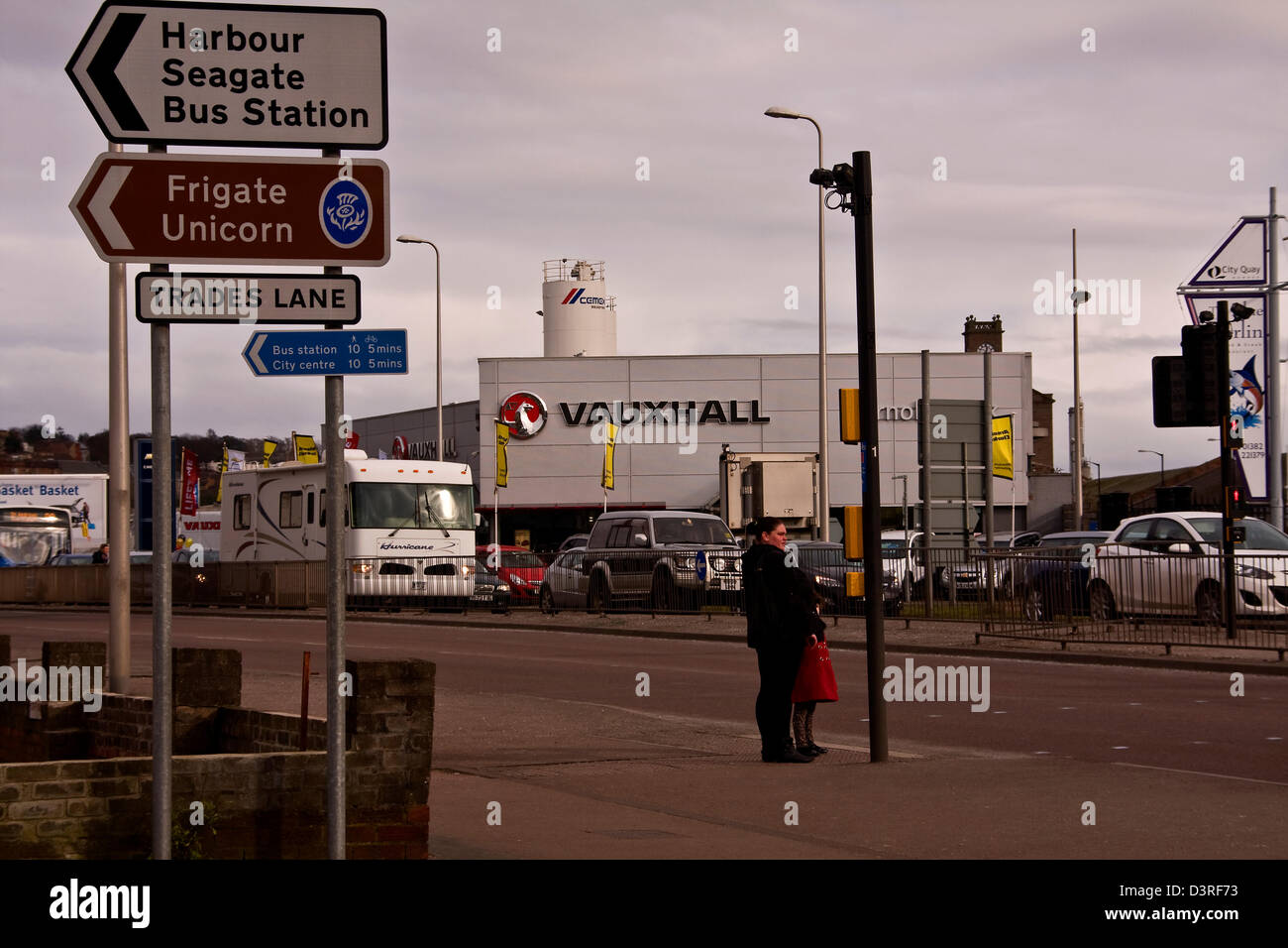People waiting at the pedestrian crossing to cross the busy road in urban Dundee, UK Stock Photo