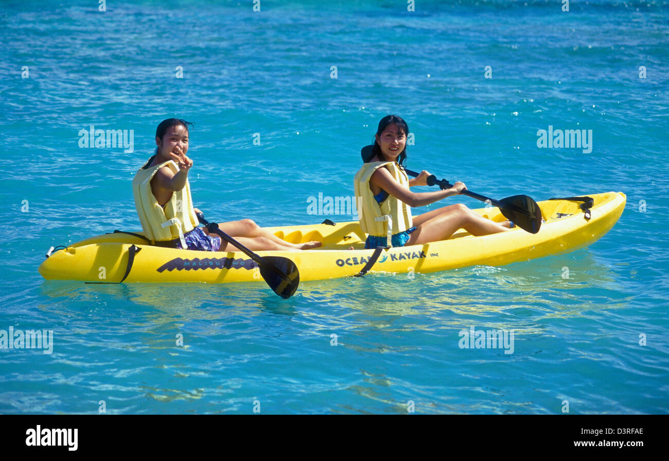 Guam, Micronesia: young Japanese women tourist in kayak at Star Sand Private Beach Club. Stock Photo