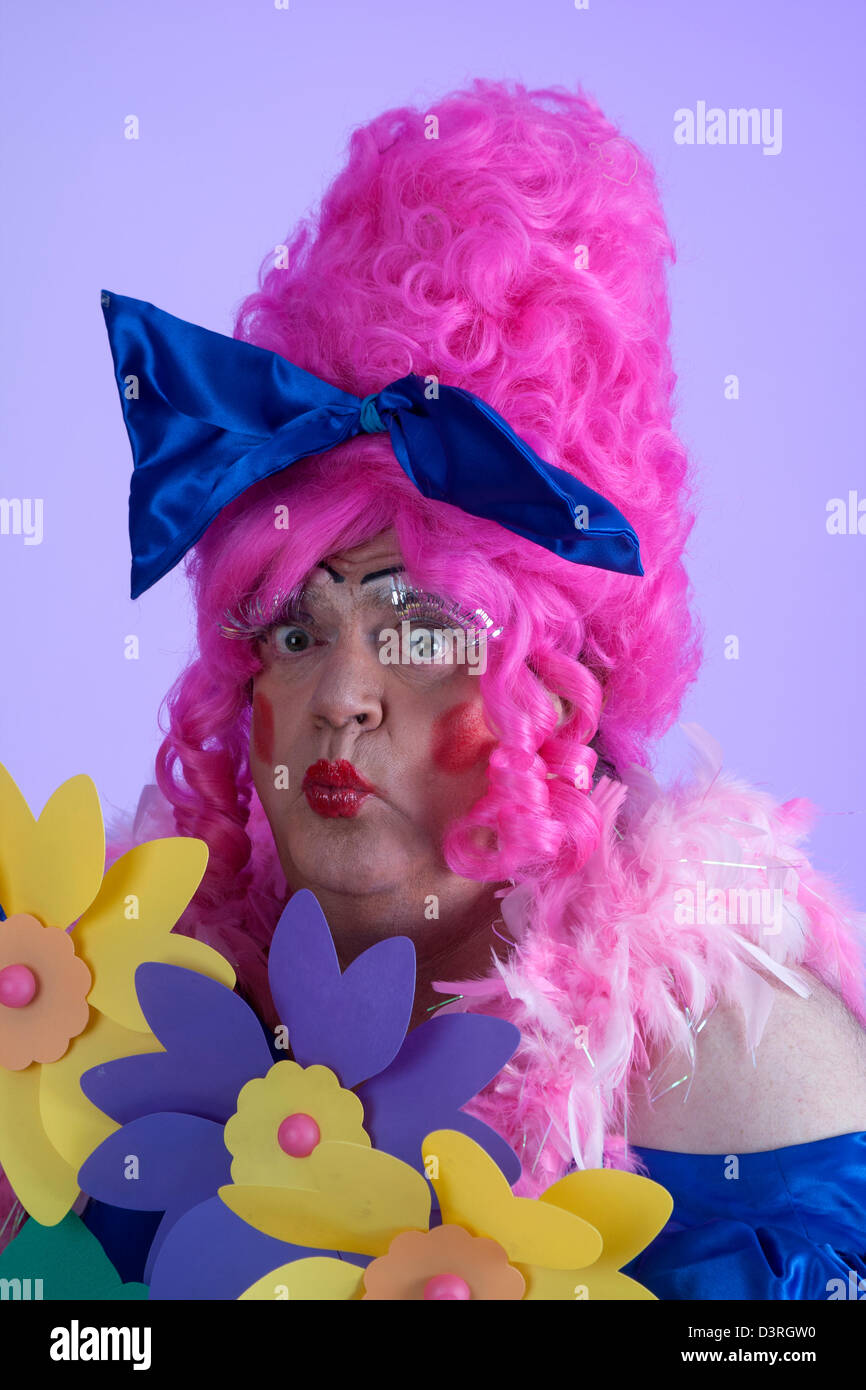 Cute pantomime dame in pink wig and blue dress blowing a kiss pout Stock Photo