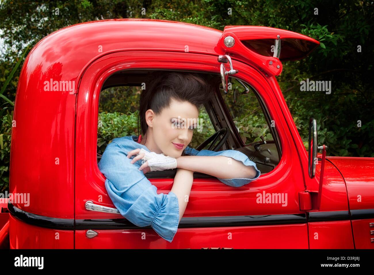 Young woman 30s sitting in red Chevy truck wearing blue denim shirt Stock Photo