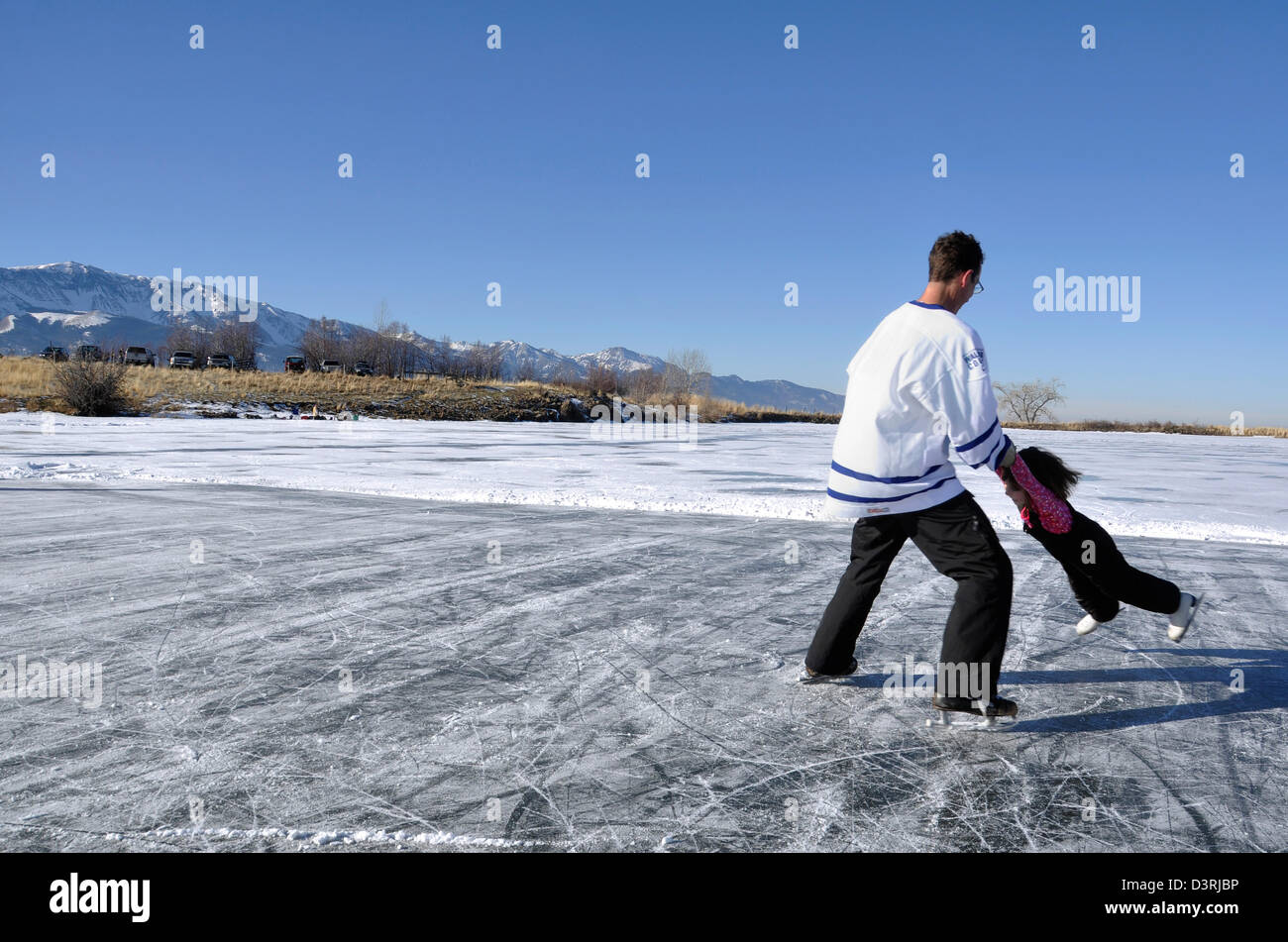 Father spinning daughter on frozen lake. Kinney Lake, Northeast Oregon. Stock Photo