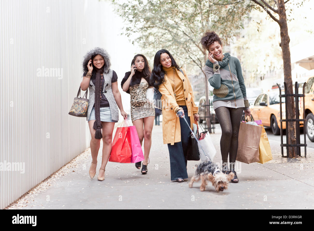 group of women friends talking on cell phone while walking Stock Photo