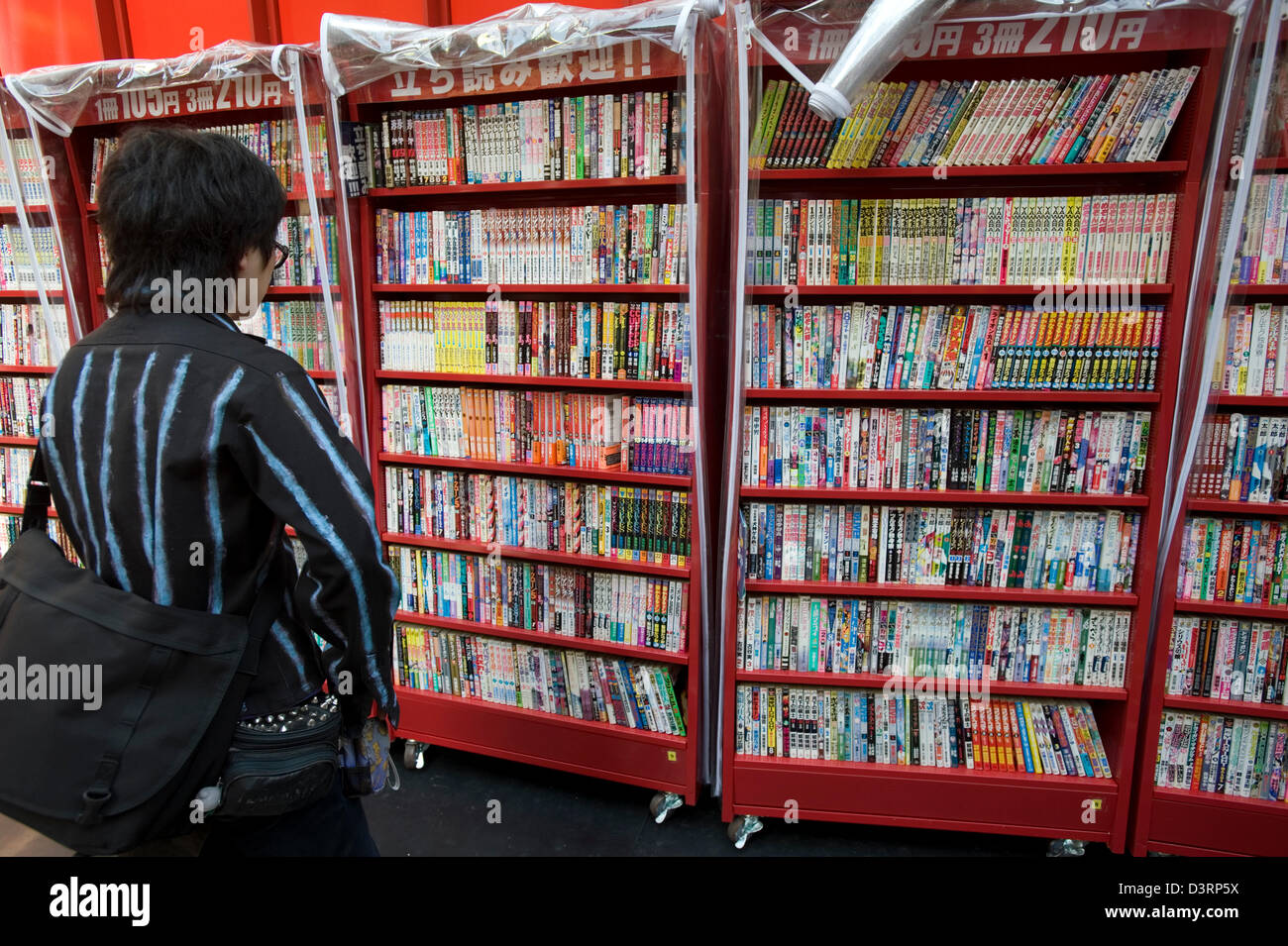 A patron browses a wide selection of used, discounted fiction and anime books at a bookstore in Osaka, Japan. Stock Photo