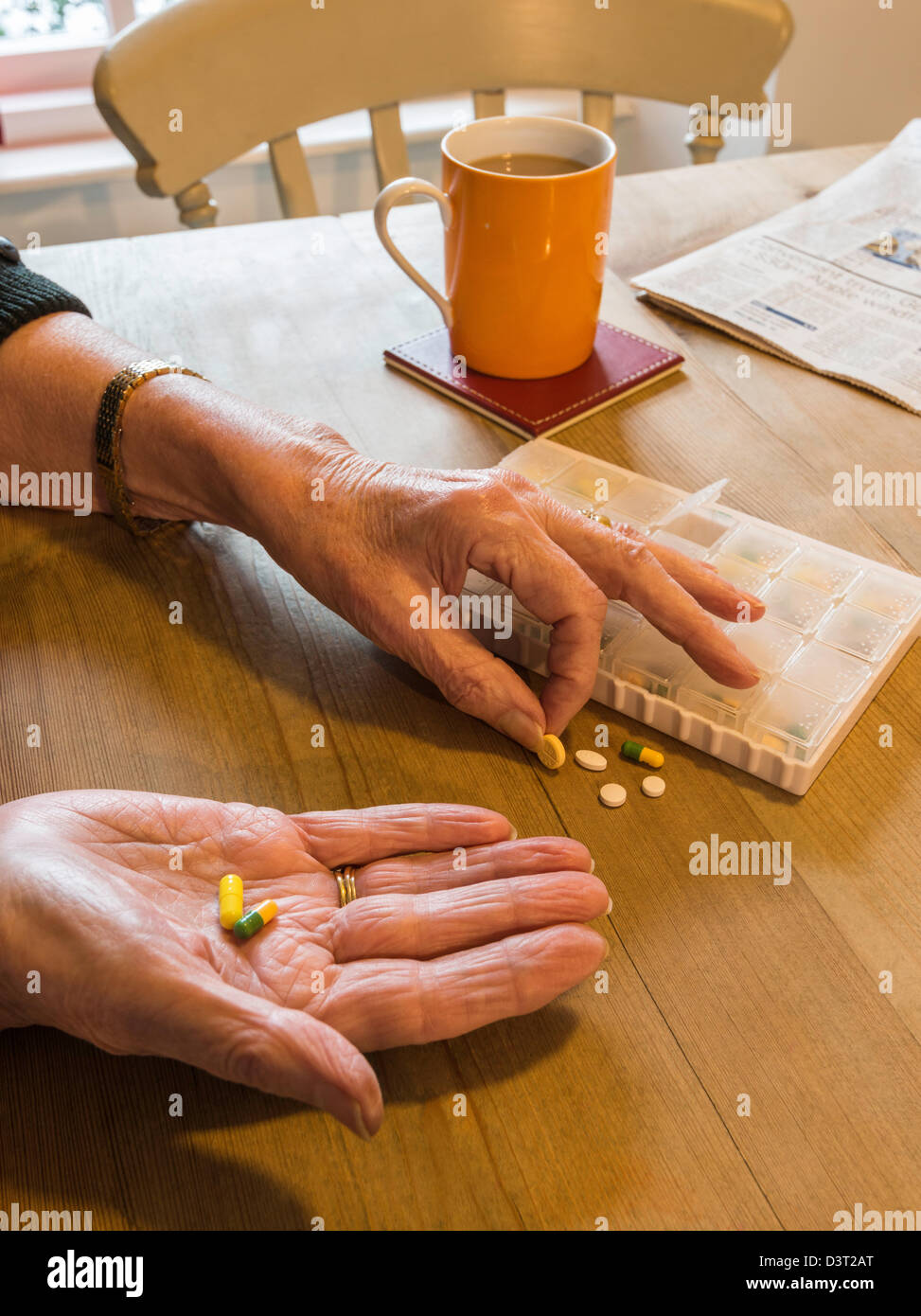 WOMAN AT TABLE WITH PILLBOX TAKING MEDICINE SORTING PILLS UK Stock Photo