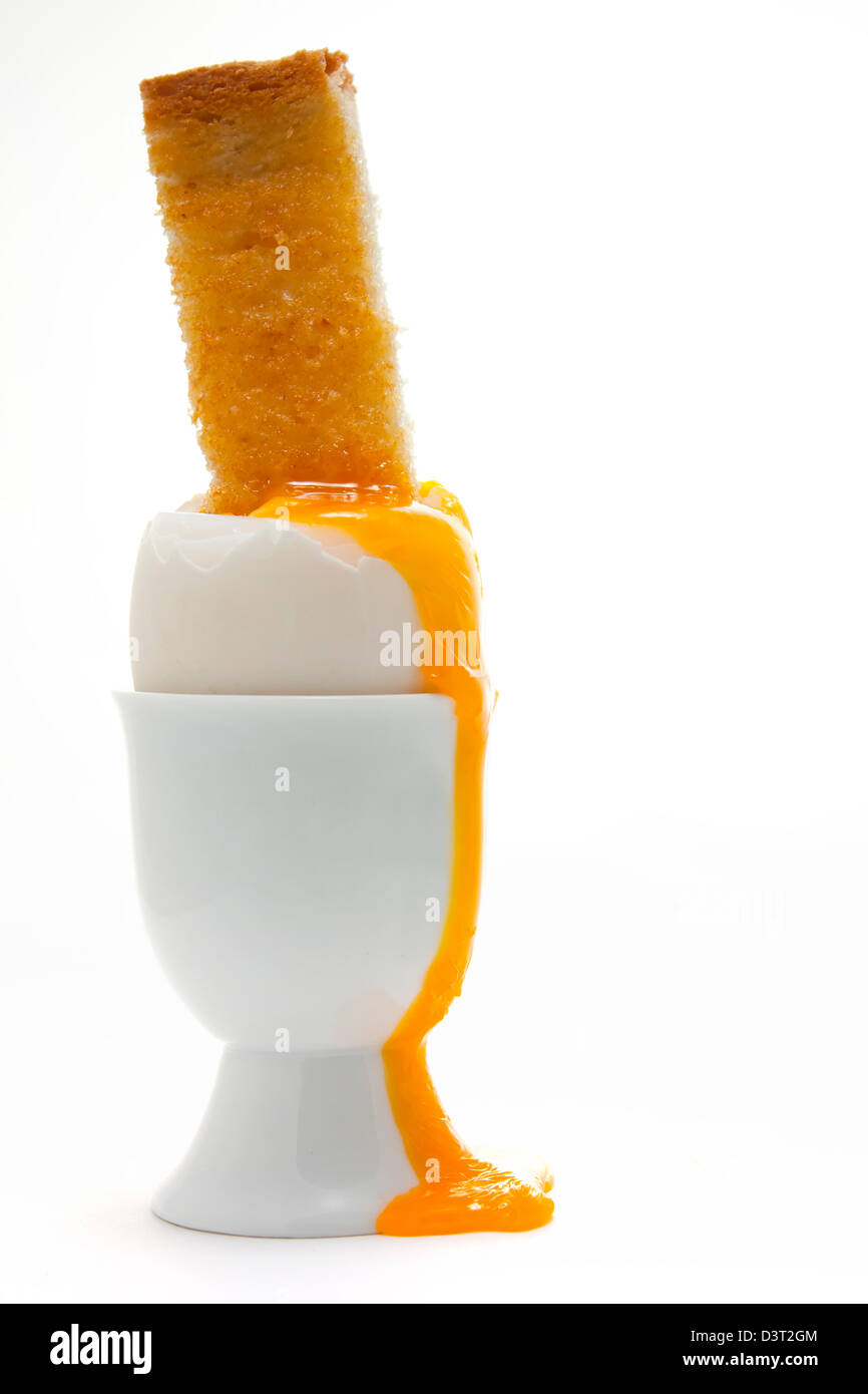 Boiled egg with a toasted soldier in an egg cup with a dripping vibrant egg yolk Stock Photo