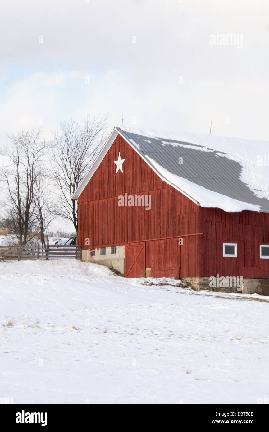 Red barn with white star in the snow, a farm in the countryside in Pennsylvania, PA, USA. Stock Photo