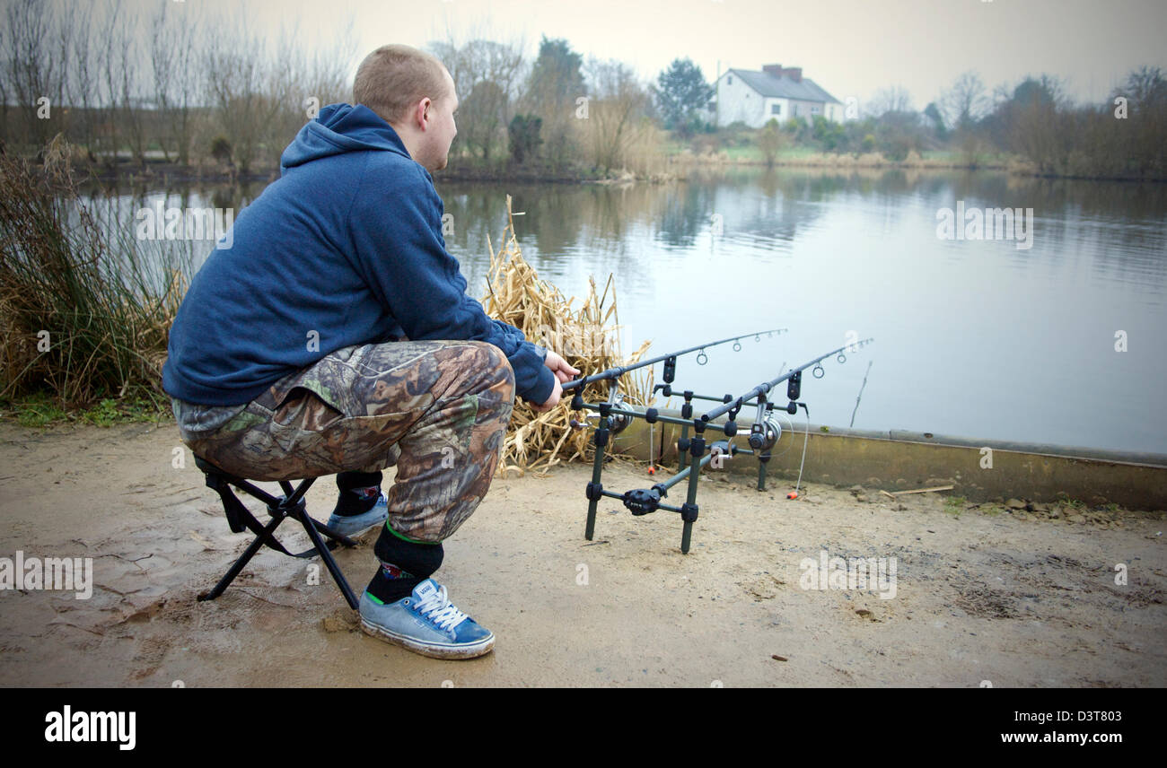 Young man fishing from a peg on the banks of a lake in winter Stock Photo