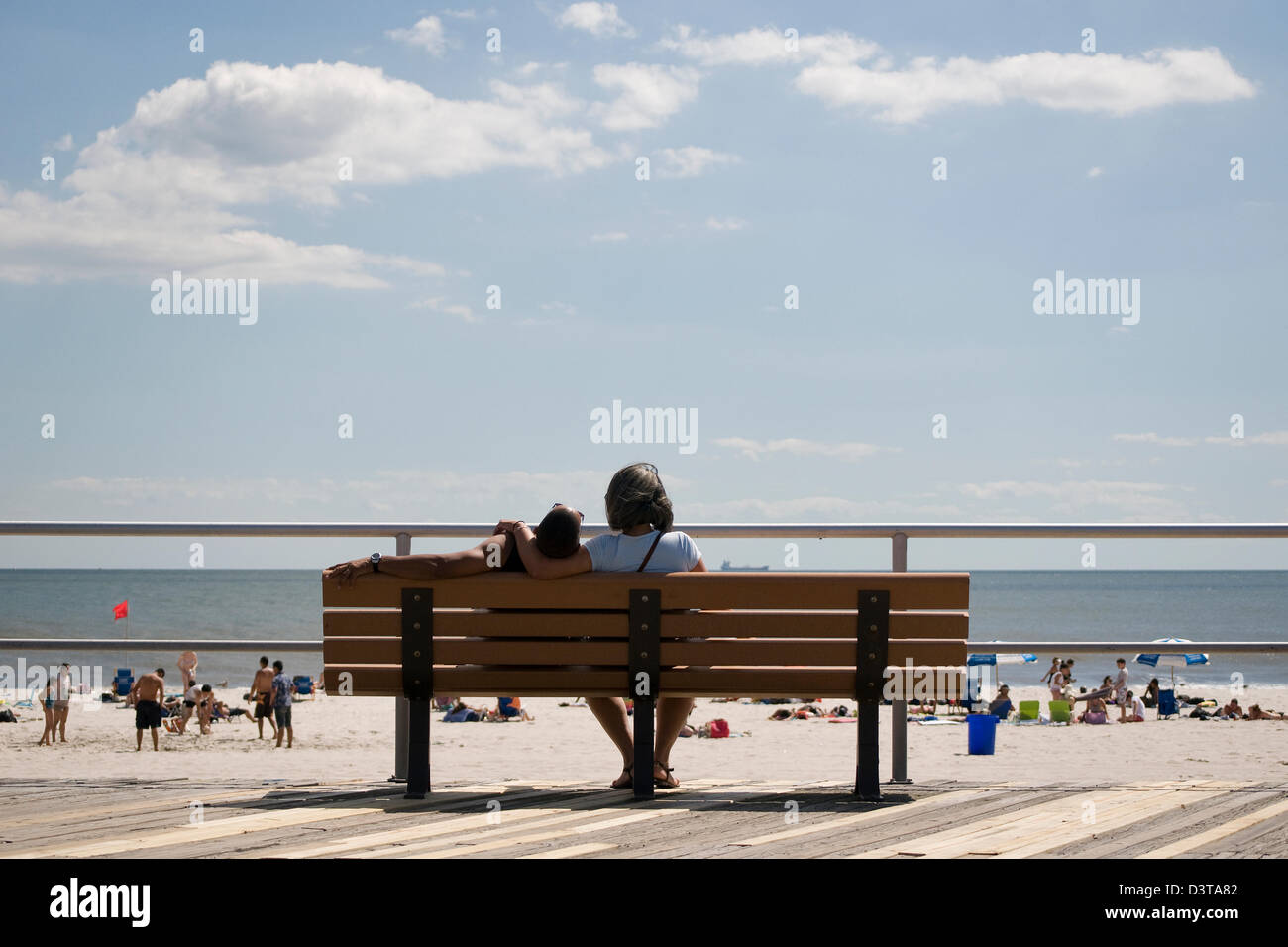 A beach-goer relaxes on a Long Beach, New York boardwalk bench. Stock Photo