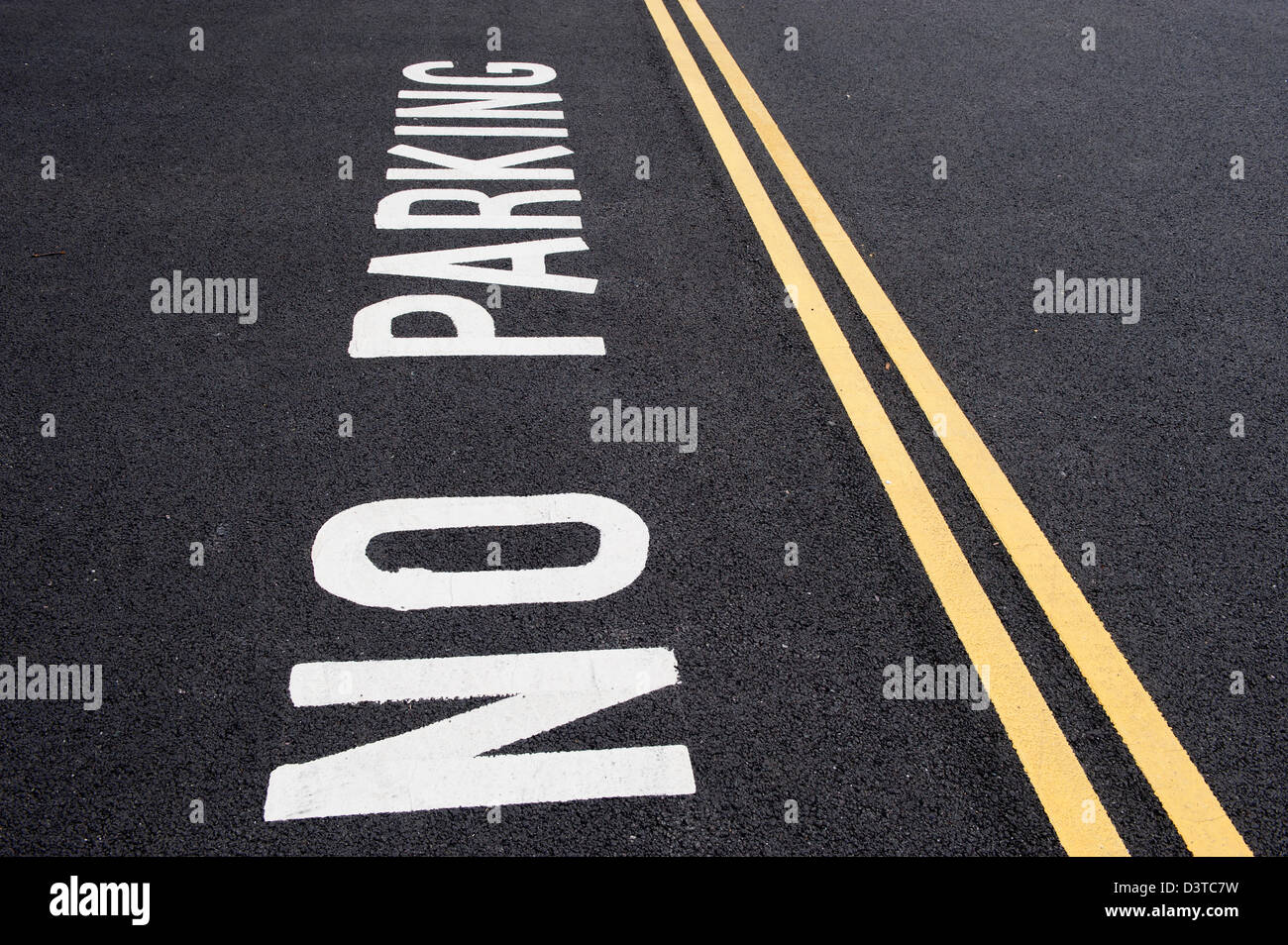 No Parking sign written on road next to double yellow lines Stock Photo
