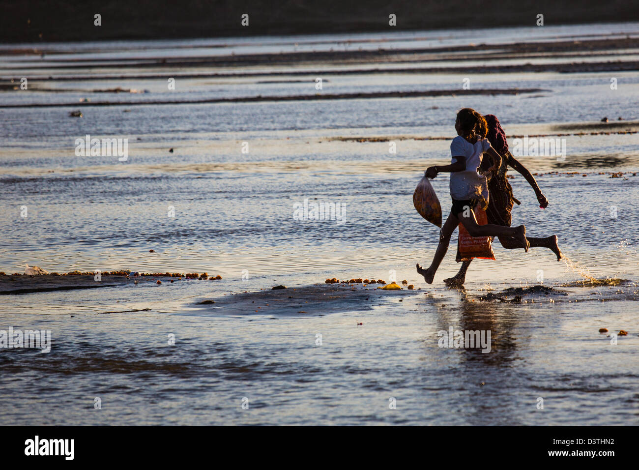 Girls collecting flowers from the river at the Kumbh Mela, Allahabad, India Stock Photo