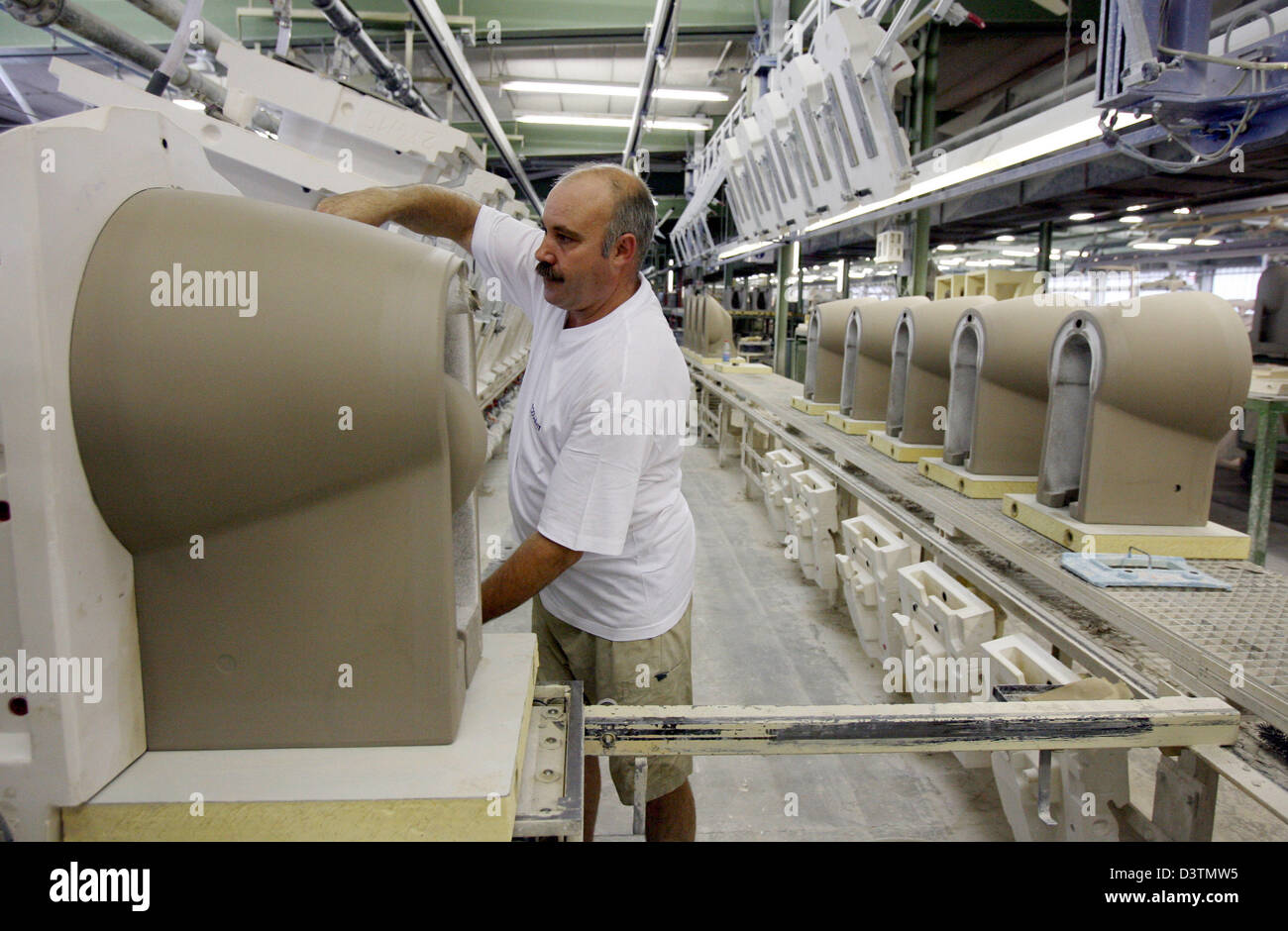 An employee of the Duravit AG takes a toilet seat from its casting mould in Hornberg, Germany, 15 September 2006. Duravit AG produces sanitary ceramics, bath room accessories and bath room furniture. Photo: Patrick Seeger Stock Photo