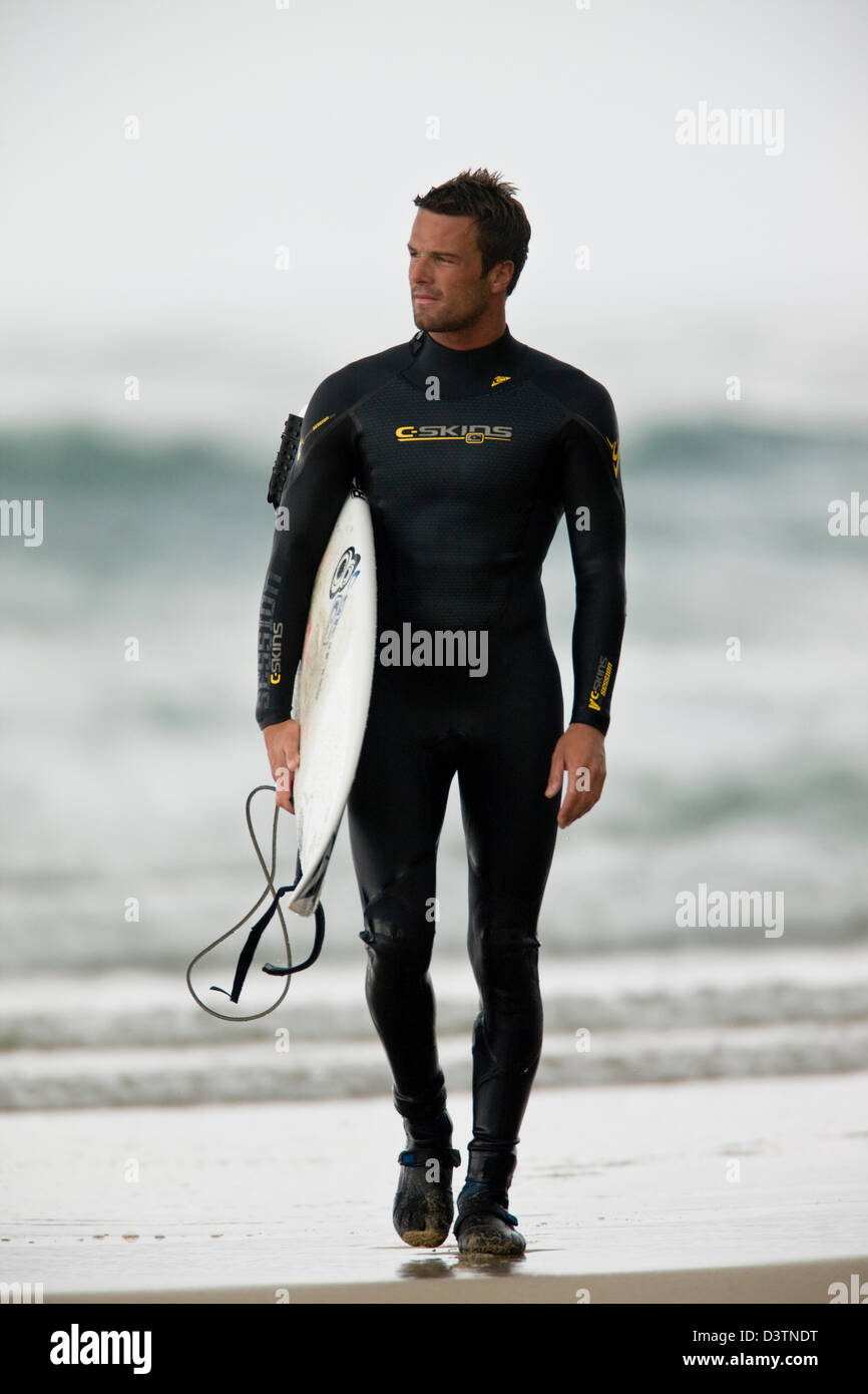 Surfer walking in wetsuit with board on wet sand, St Agnes, Cornwall, UK Stock Photo Alamy