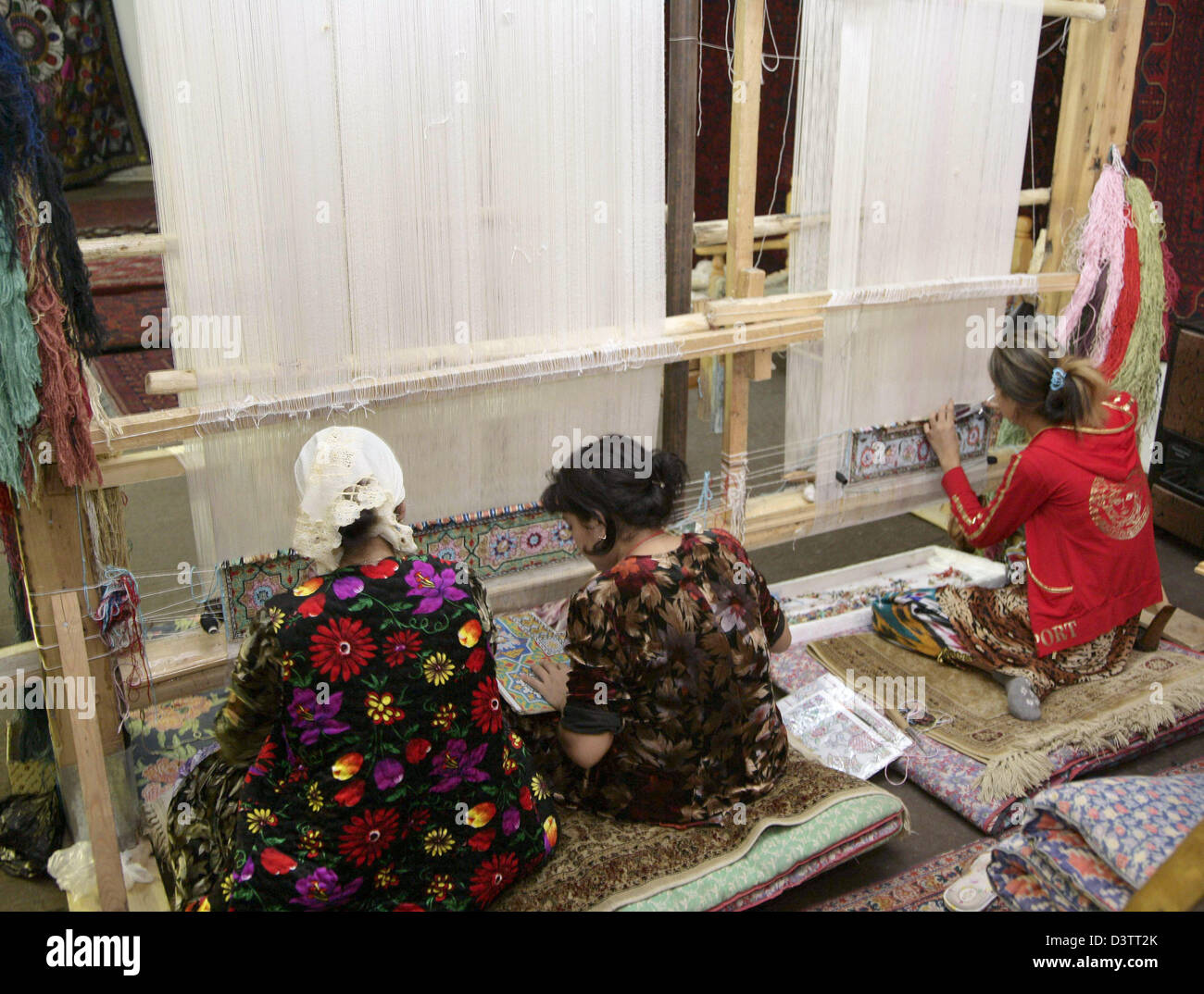 Three women weave silk carpets in a weavery in Bukhara, Uzbekistan, Thursday, 02 November 2006. Photo: Peer Grimm Stock Photo
