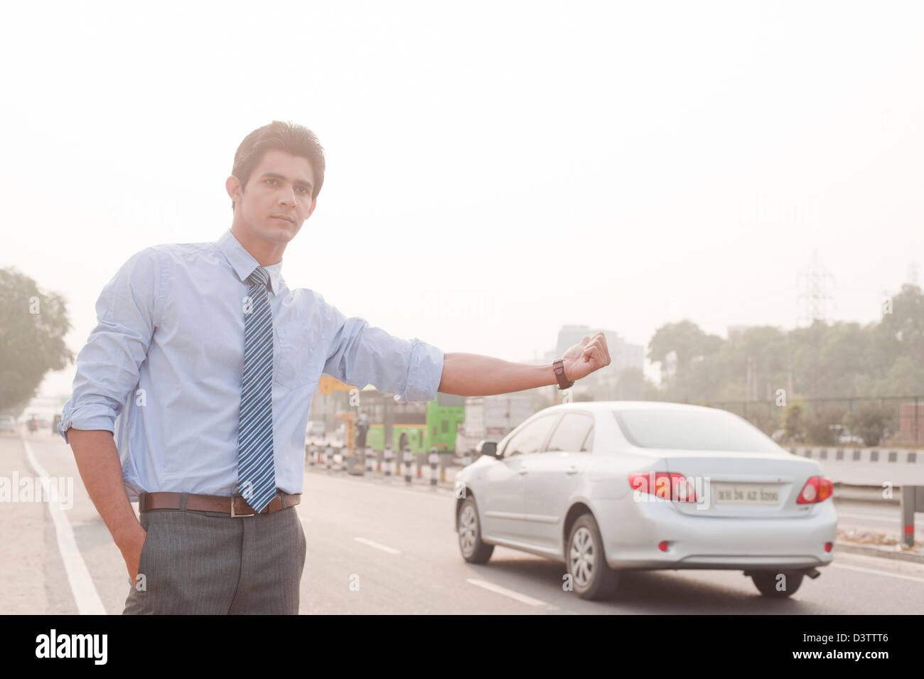 Businessman hitchhiking, Gurgaon, Haryana, India Stock Photo