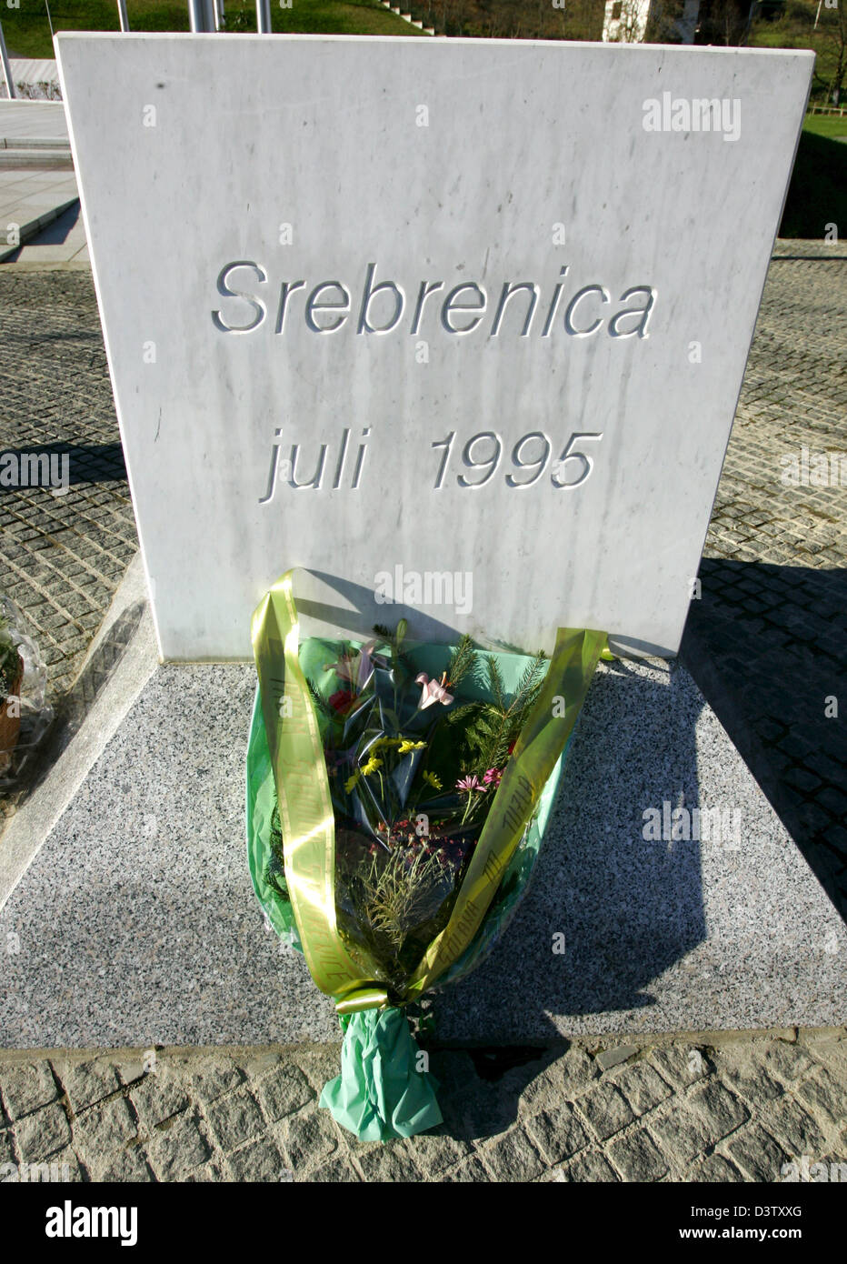 A bunch of flowers lies in front of a marble cuboid with the letters 'Srebrenica juli 1995' at the memorial site for the 8.000 murdered boys and men of Srebrenica in Potocari near Srebrenica in Bosnia and Herzegovina, 15 Novemeber 2006. The city set the sad scene for a massacre in July 1995, when Bosnian Serbs under the commando of General Ratko Mladic invaded the city and slaughte Stock Photo