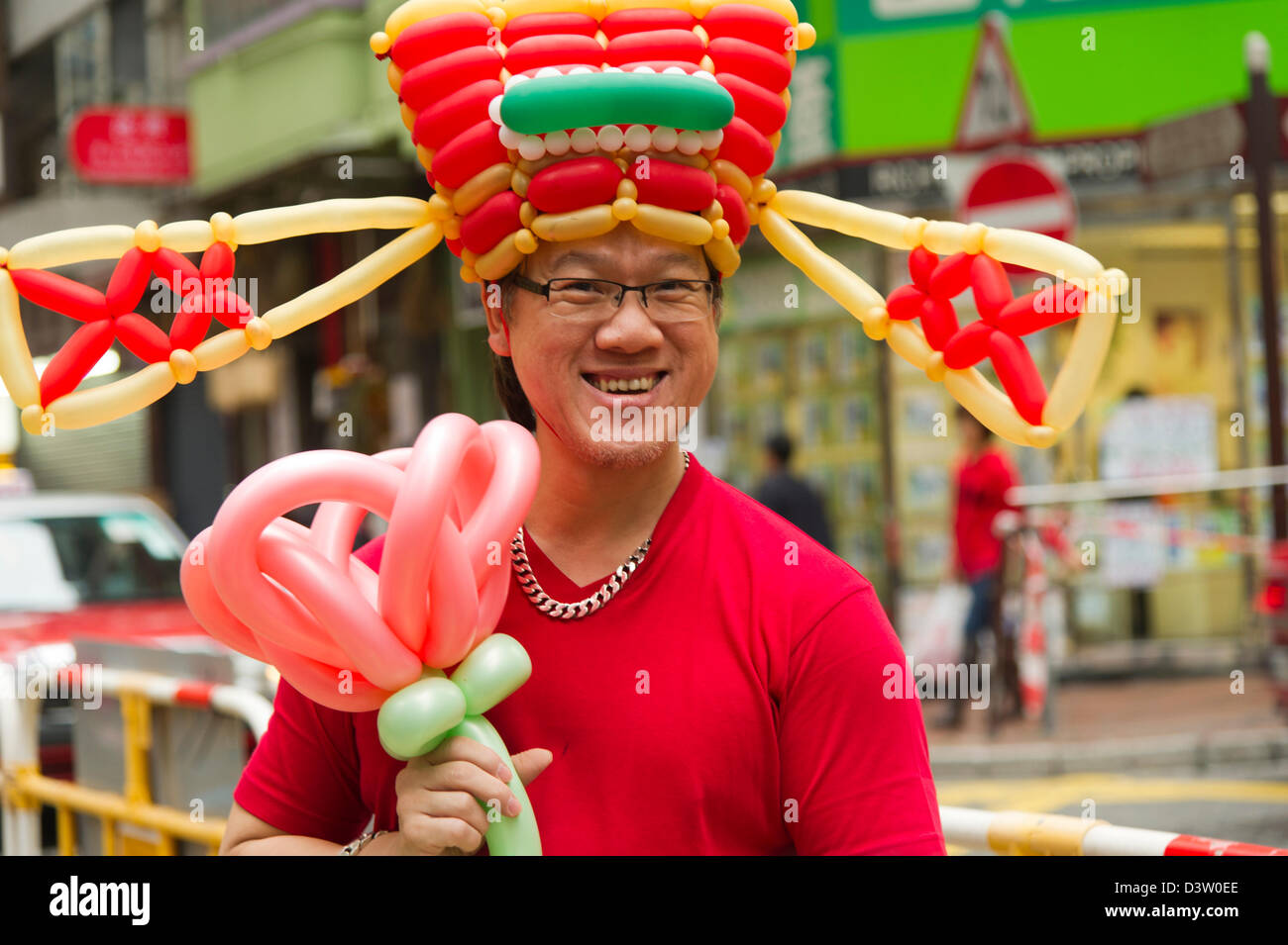 A smiling street artist shows off the balloon creation he has made Stock Photo