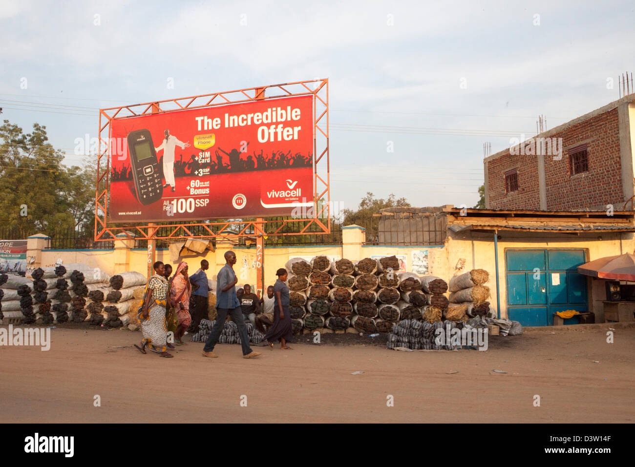 JUBA, SOUTH SUDAN, 19th November 2012: Charcoal street seller and mobile phone poster. Stock Photo