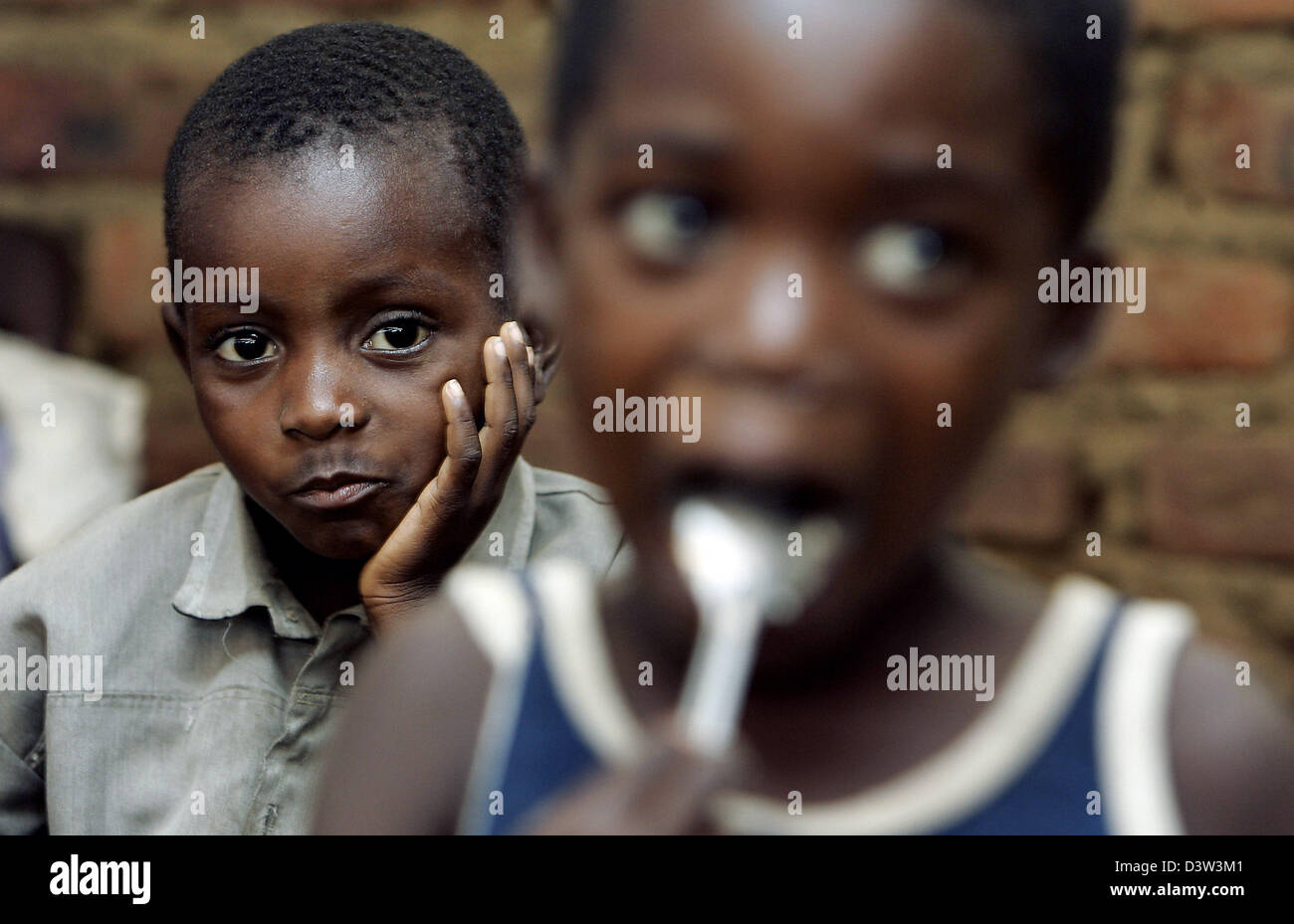 (dpa file) A boy props his head on his hand while another little boy