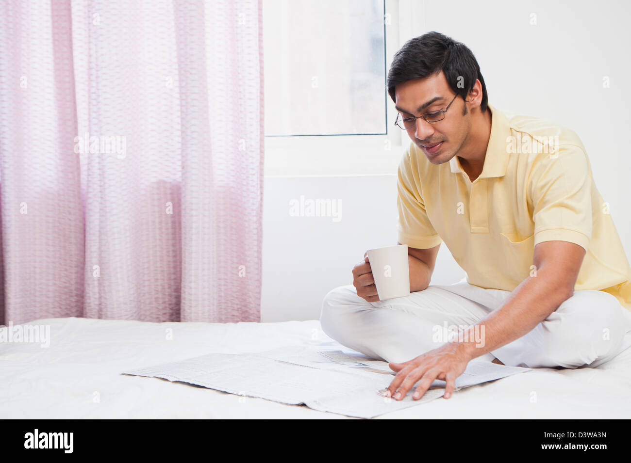 Bengali man reading a newspaper and having coffee Stock Photo