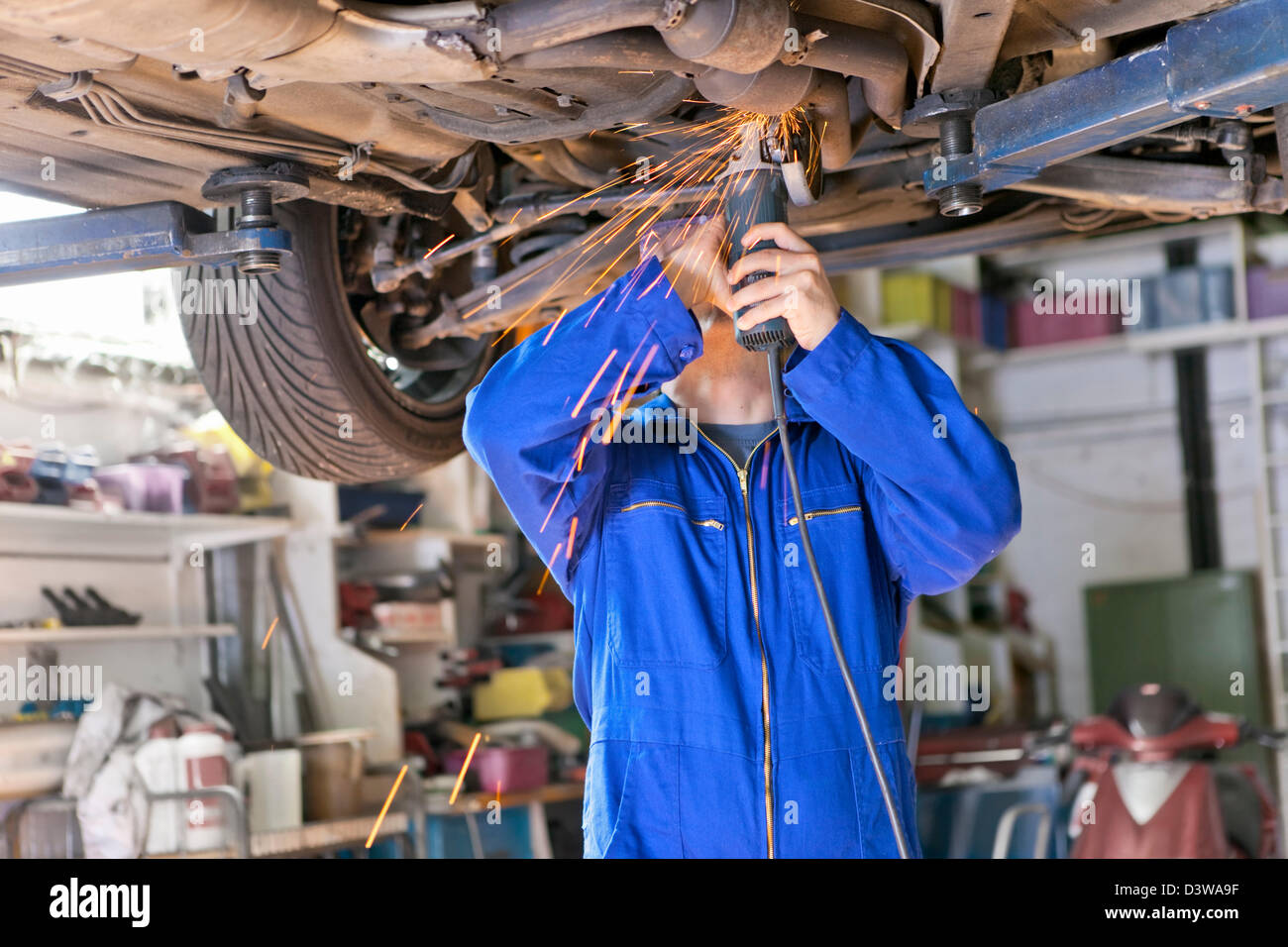 An auto mechanic works on chassis of car in his small business of car