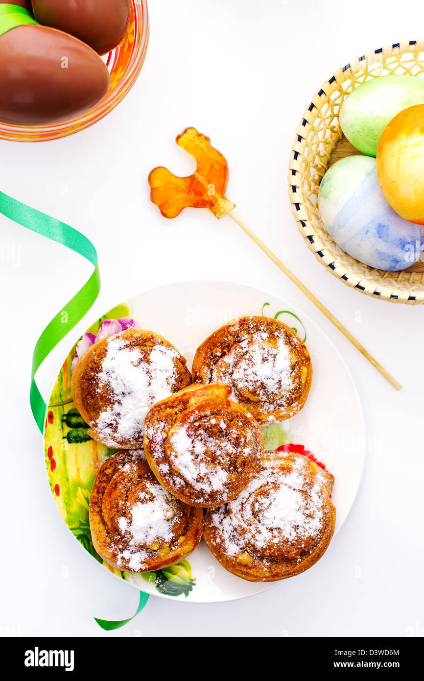 Easter eggs with plate of sweet rolls and lollipop Stock Photo