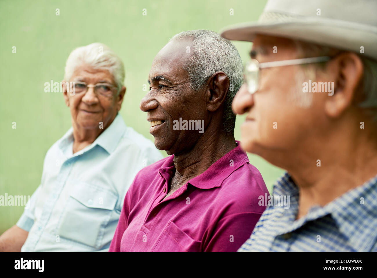 three senior men sitting on bench in park and talking Stock Photo