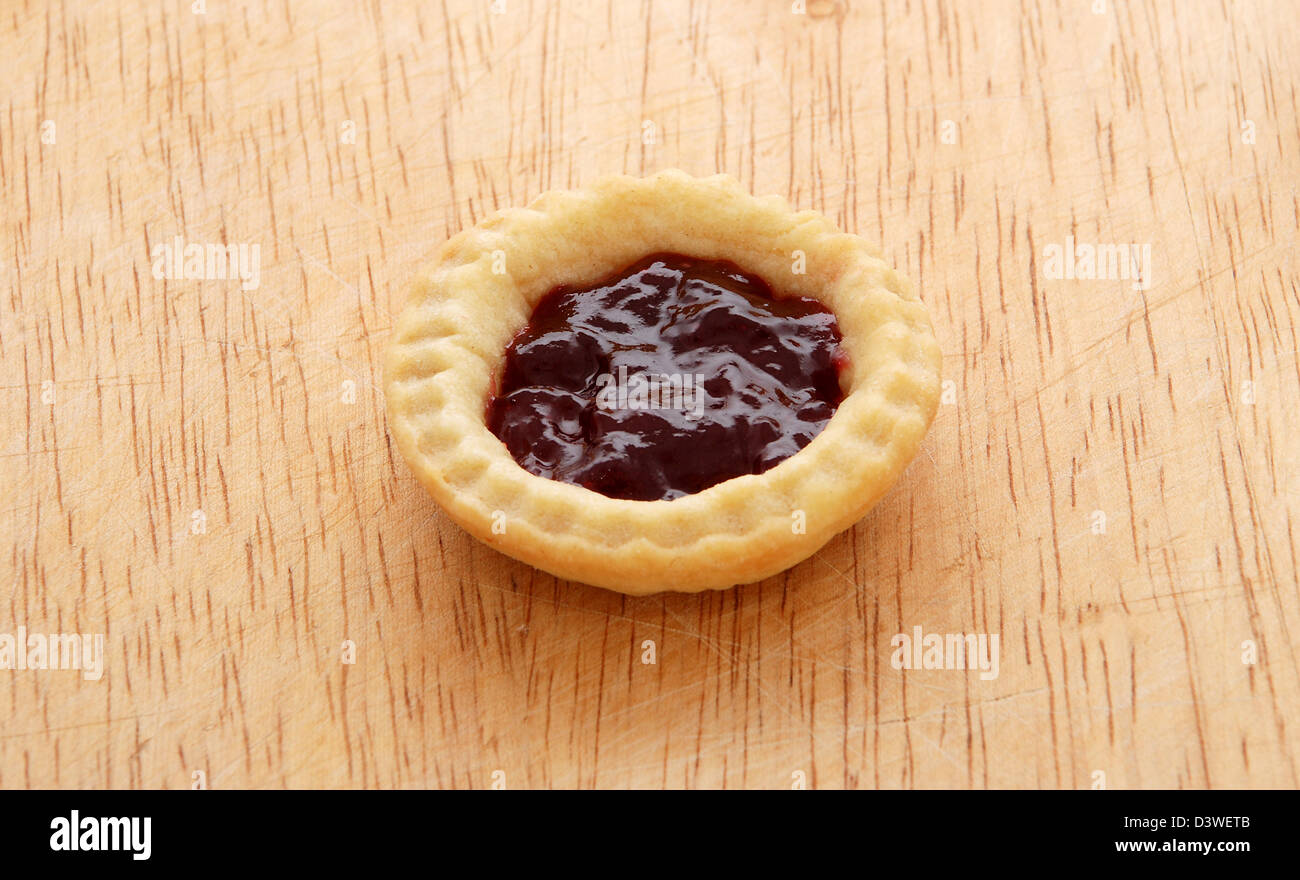 Single tasty jam tart sitting on a wooden table Stock Photo