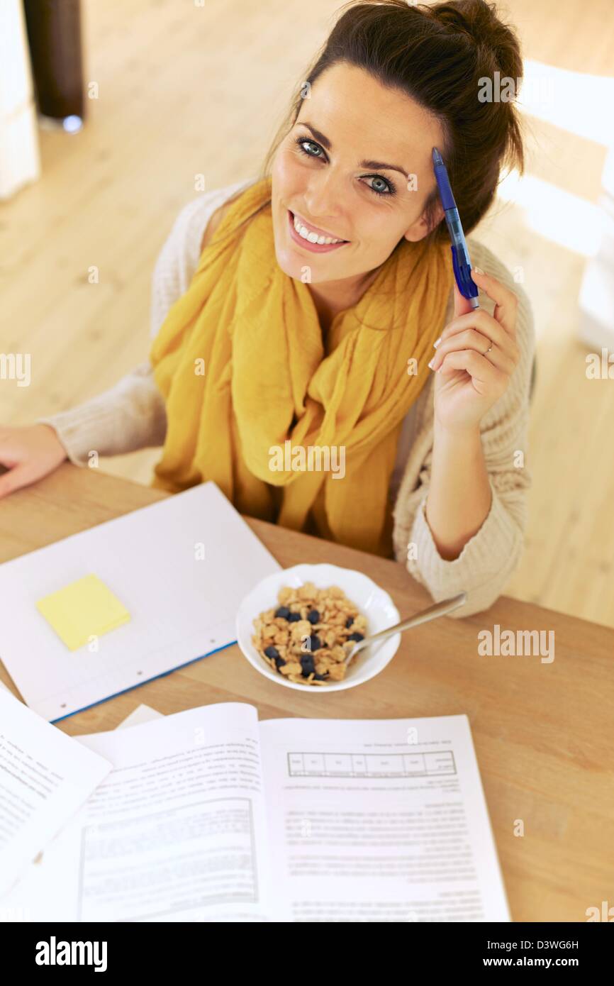 Multitasking student having her breakfast while studying Stock Photo ...