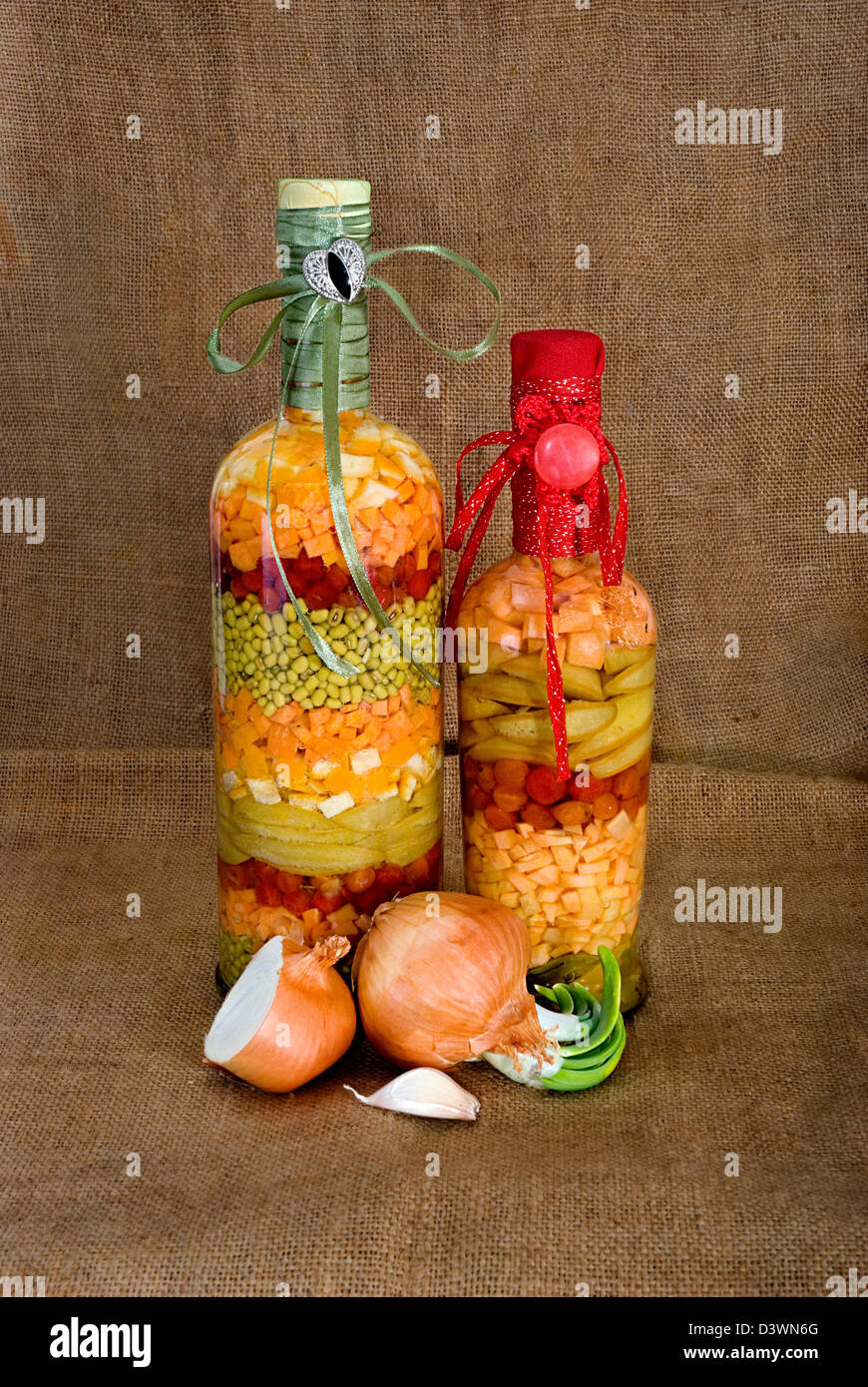 Onions, garlic and two bottles with tinned vegetables Stock Photo