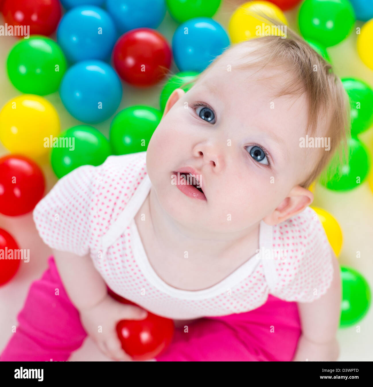 Portrait of cute baby girl playing among colorful balls Stock Photo