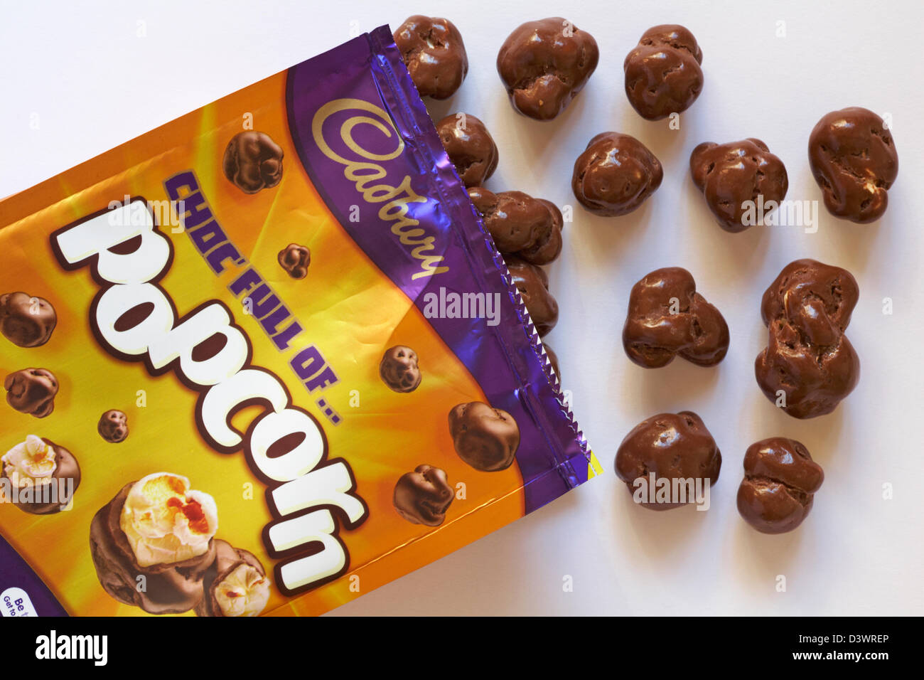 Bag of Cadbury choc full of popcorn opened with contents spilled set on white background Stock Photo
