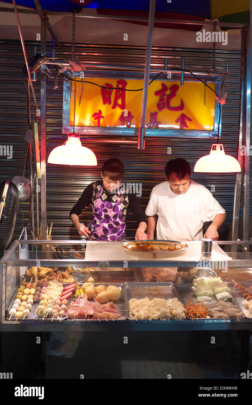 Street vendor couple selling fish balls and other delicacies in late night Macau, China SAR Stock Photo